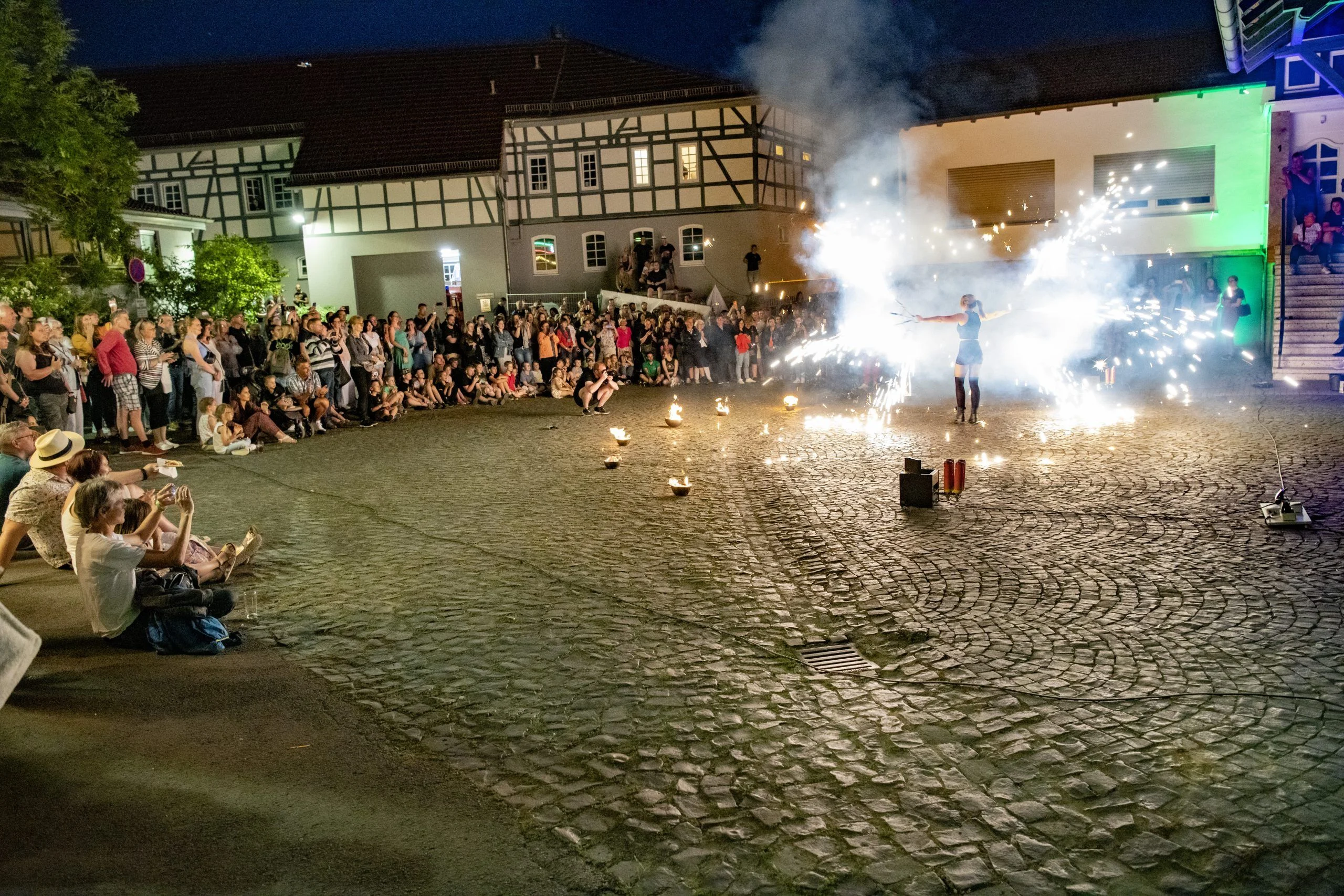 Höfe- und Scheunenfest: Publikum sitzt im Kreis um die Feuershow auf dem Kopfsteinpflaster