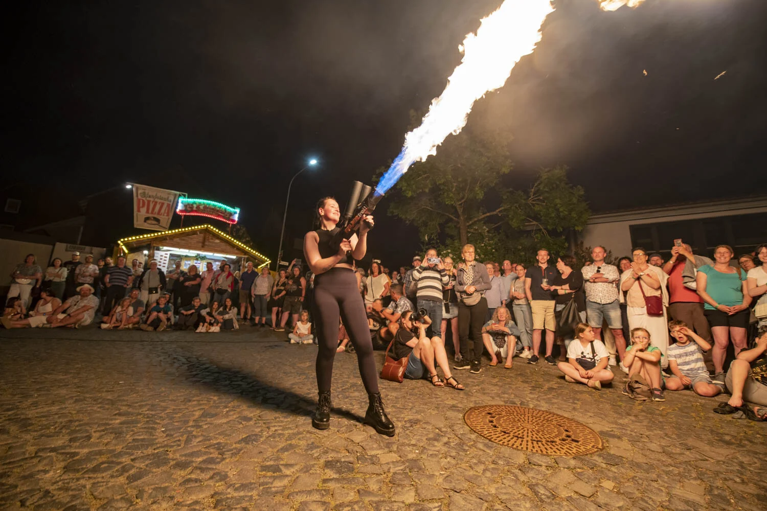 Artistin mit Flammenwerfer vor einer dichten Menschenmenge