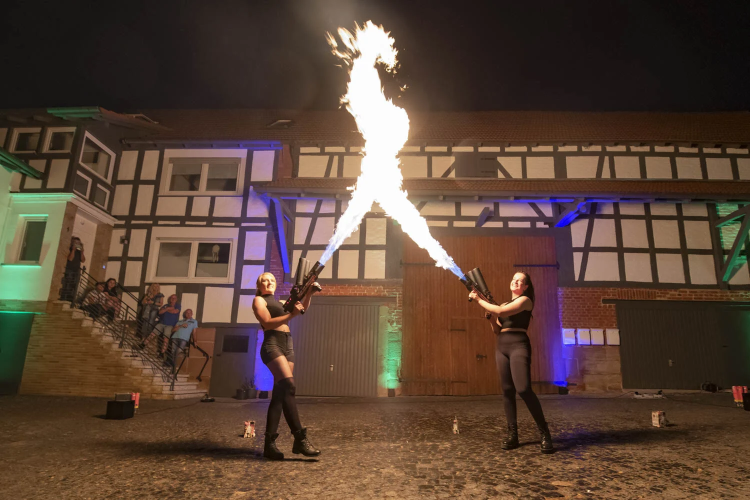 Zwei Artistinnen schießen Flammen in den Nachthimmel vor einem Fachwerkhaus