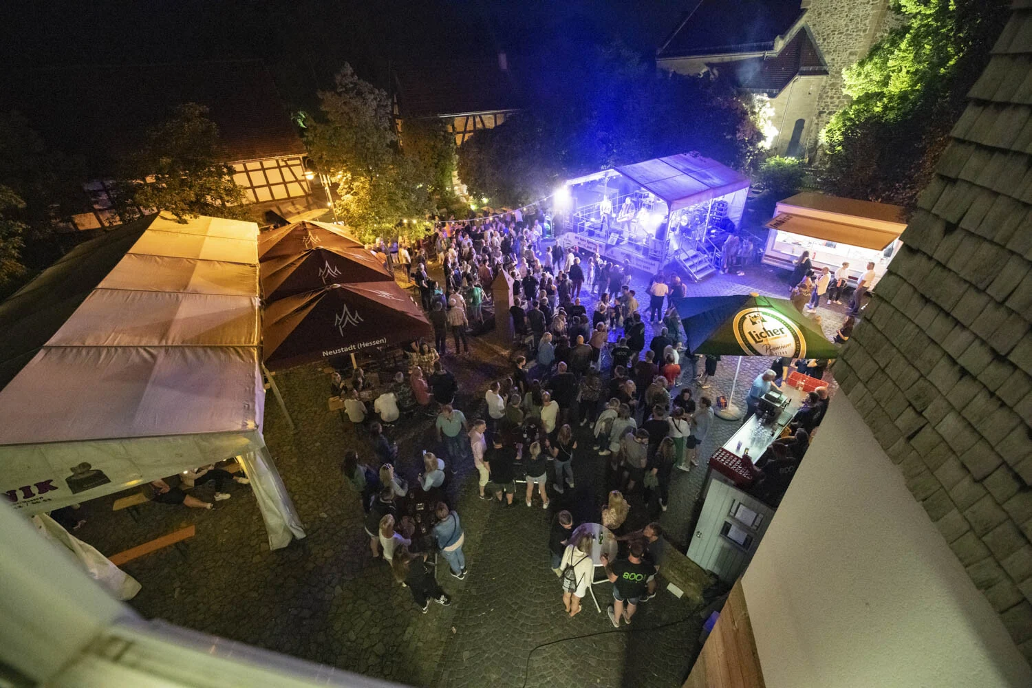 Blick von oben auf Zelte und feiernde Menschen bei Nacht