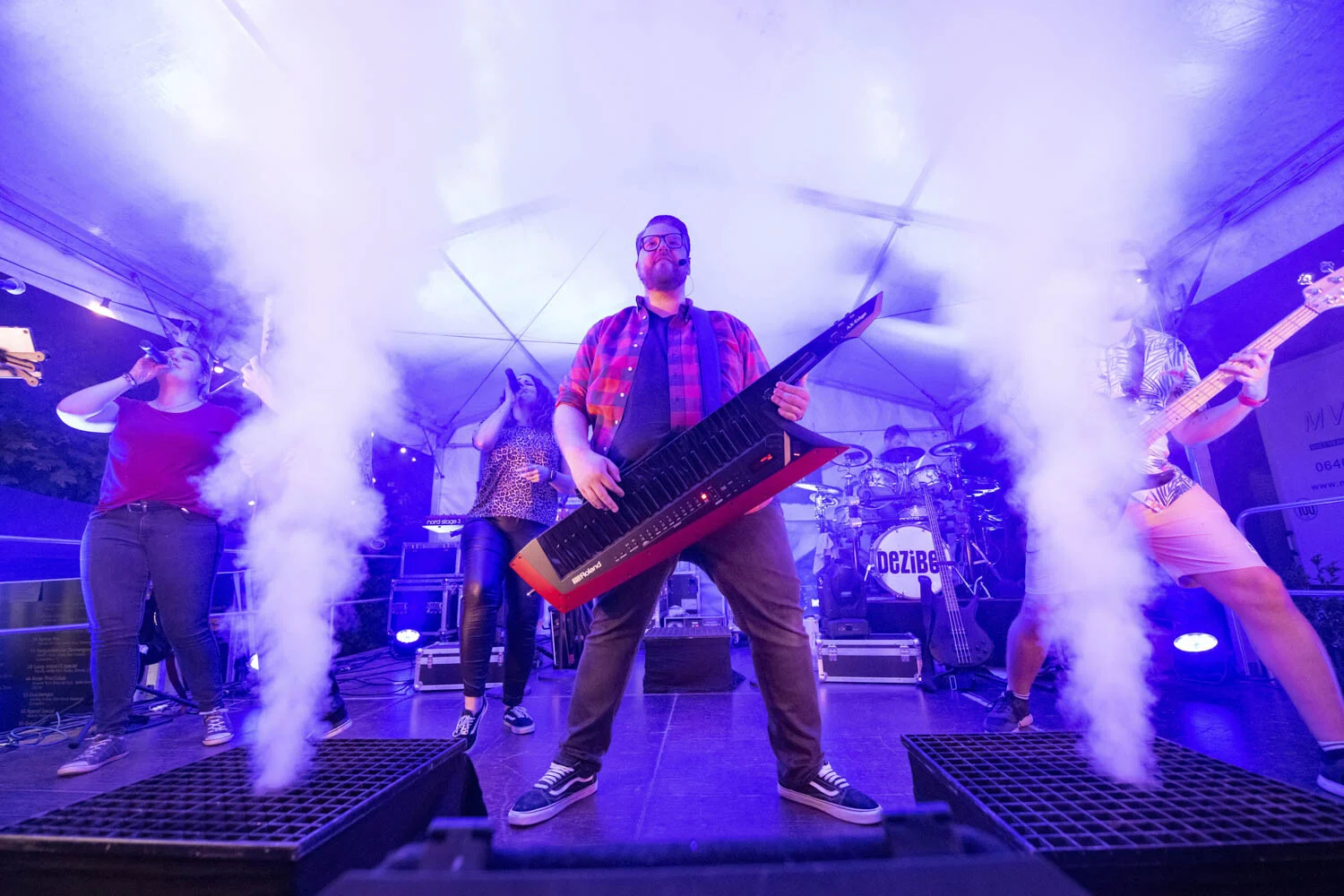 Musiker mit rotem Keytar auf der Bühne zwischen zwei Nebelfontänen im blauen Licht