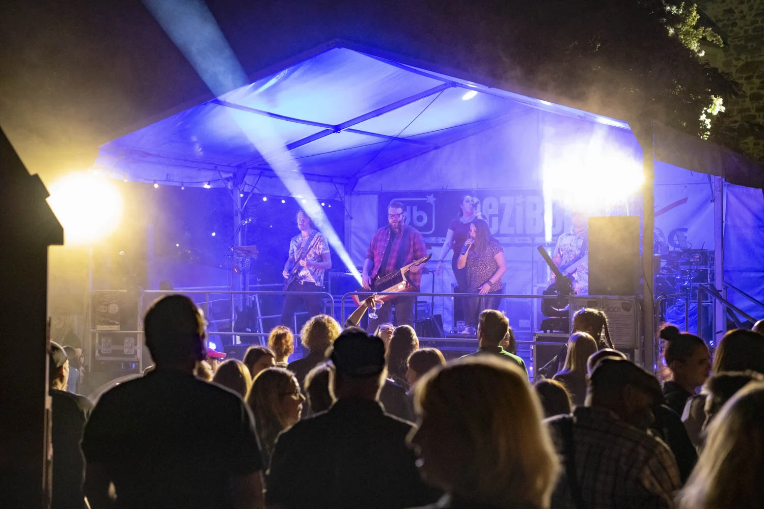 Zuschauer stehen vor einer blau beleuchteten Bühne mit Band