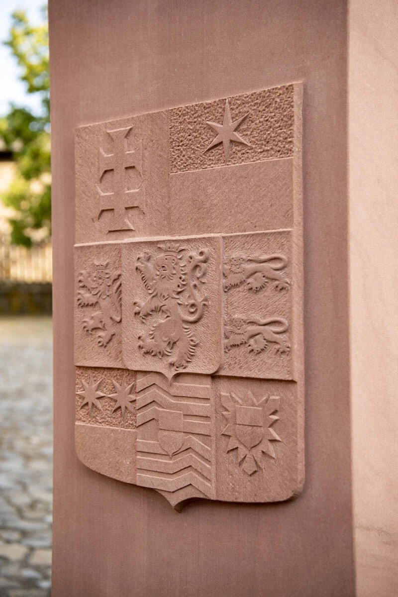 Nahaufnahme des Wappens mit Kreuz, Stern und Löwen im Stein