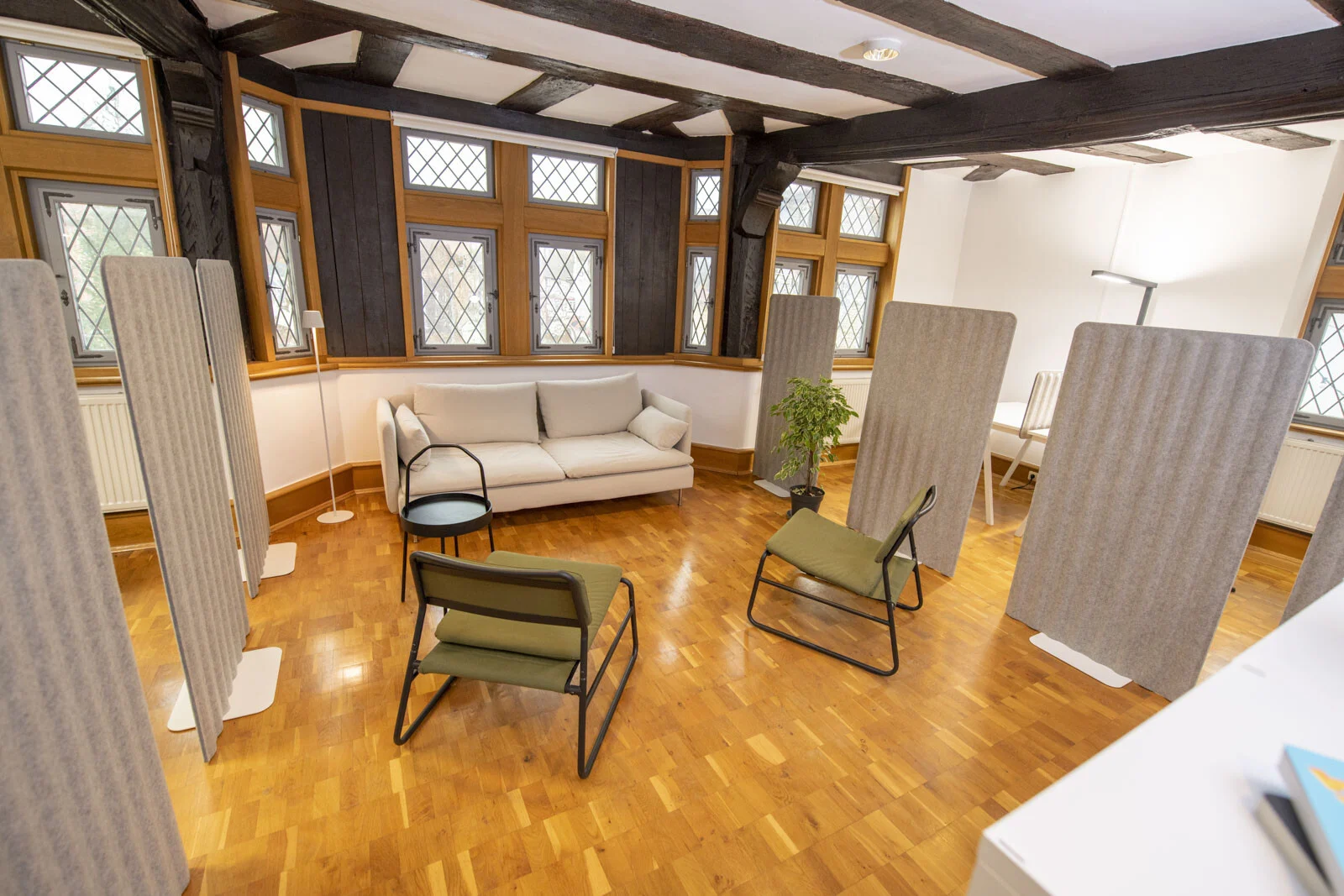 Coworking Space in Neustadt: Raum mit Holzbalken, Bleiglasfenstern, Sofa und Stellwänden