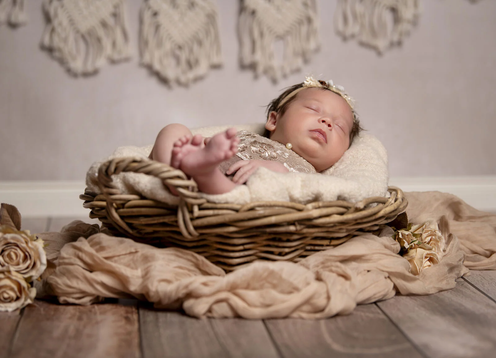 Babyfotografie: Baby mit Haarband schläft tief im Körbchen auf einem Holzboden