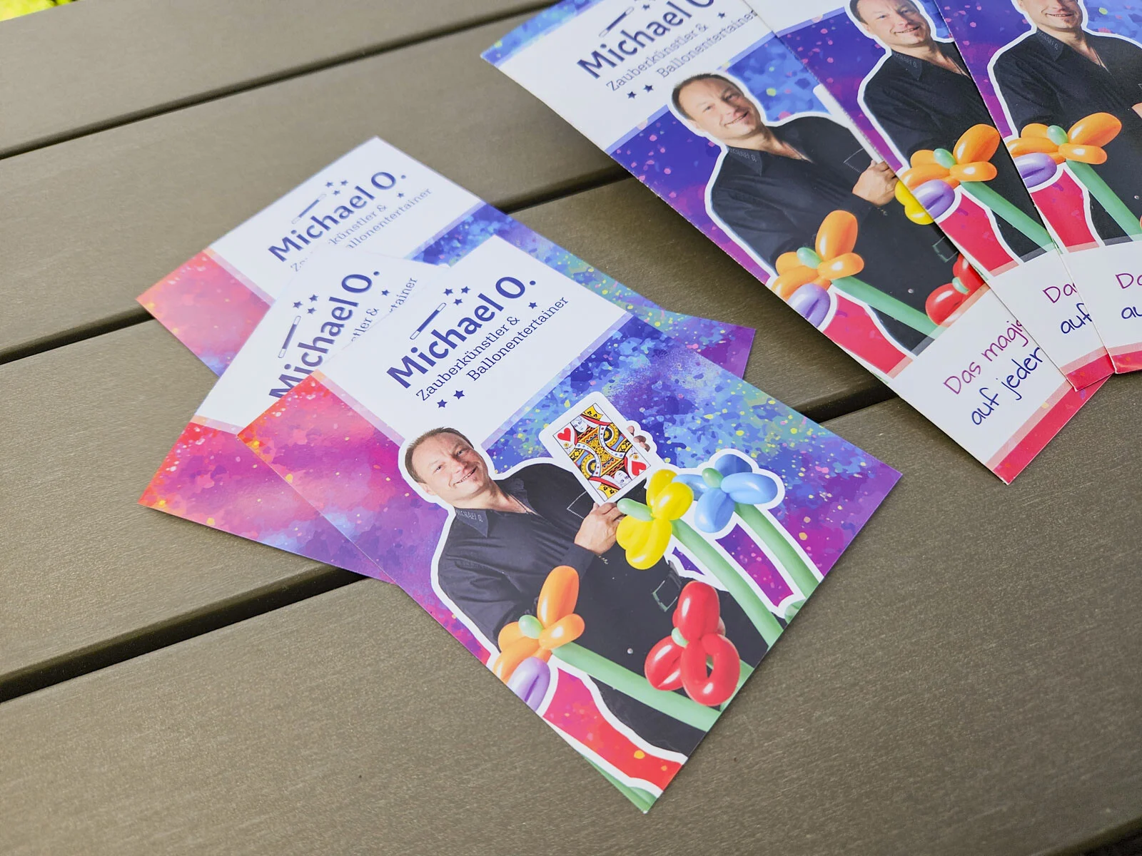 Karten mit dem Werbefoto des Zauberkünstlers, einer Spielkarte und bunten Ballonfiguren