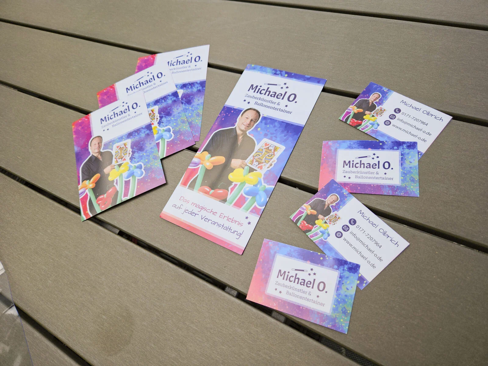 Mehrere Flyer und Karten im neuen Design liegen verteilt auf einem Gartentisch