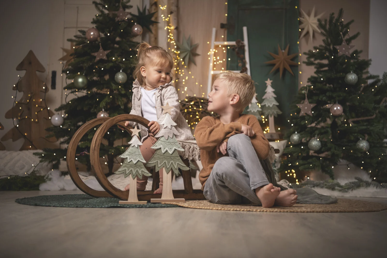 Weihnachtsaktion 2024: Mädchen sitzt auf einem Holzschlitten, ihr Bruder lacht daneben