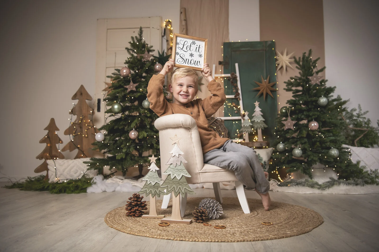 Weihnachtsaktion 2024: Junge hält auf dem Sessel ein Schild mit Let it Snow hoch