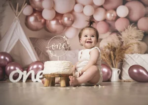 Cake Smash zum ersten Geburtstag vor rosa Luftballons und großer One-Deko