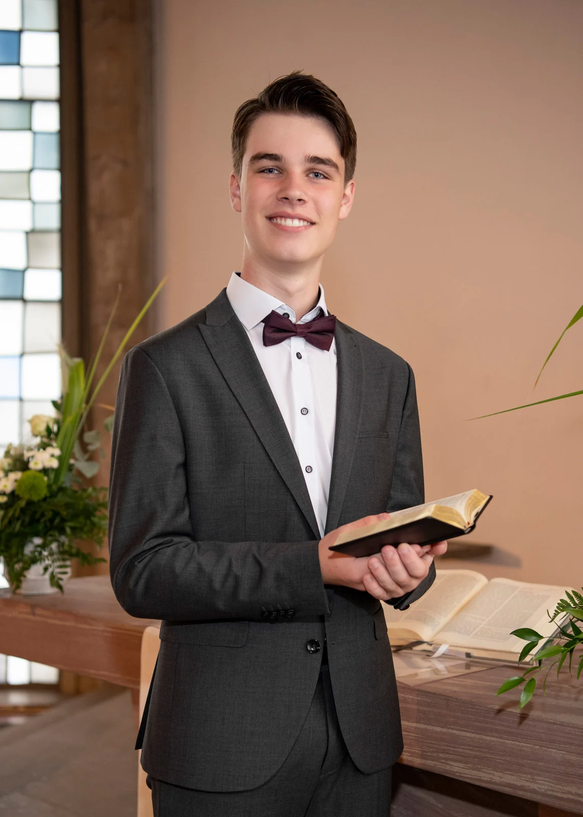 konfirmation kommunion taufe | Peter Lauritis Photography Konfirmand im Anzug liest lächelnd in seiner Bibel