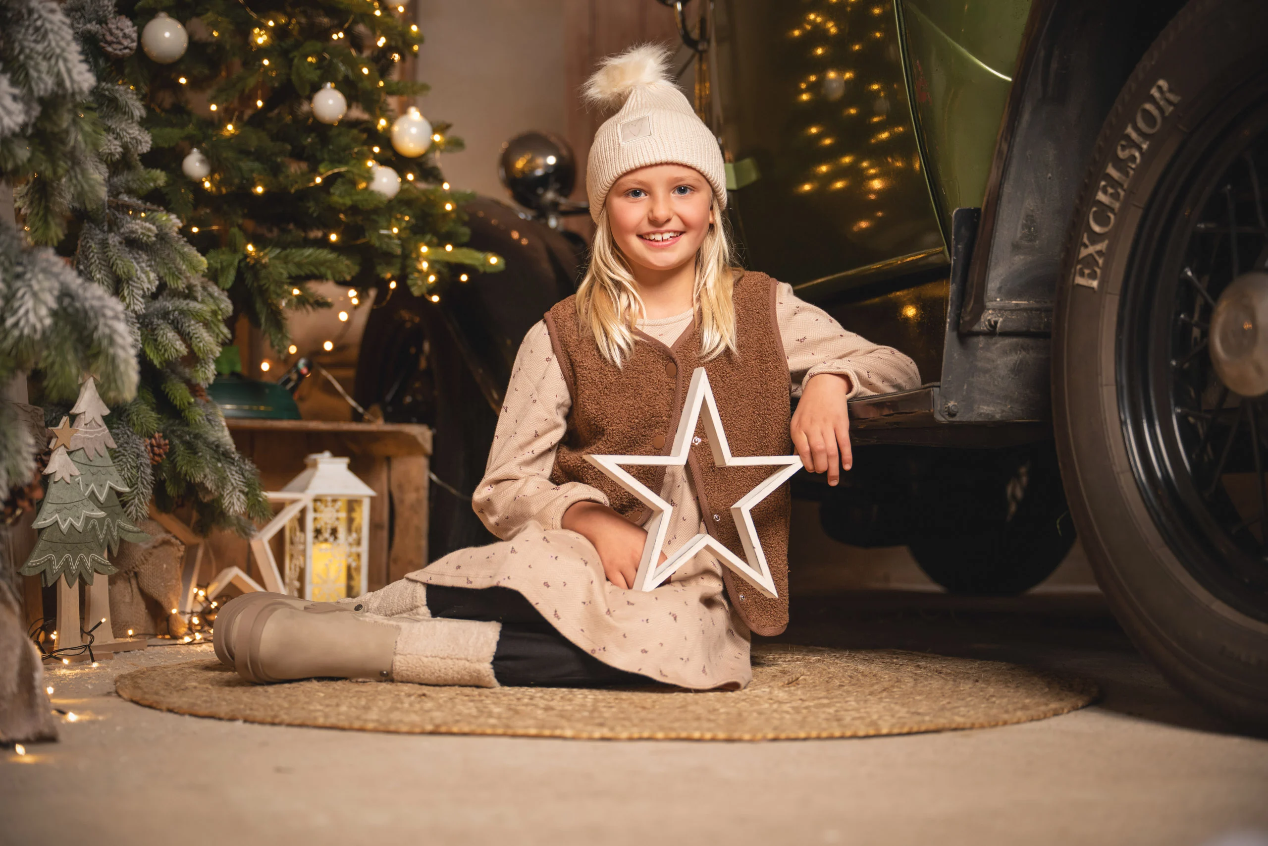 Fotoaktion am Pickup: Mädchen sitzt mit einem weißen Stern vor einem geschmückten Tannenbaum