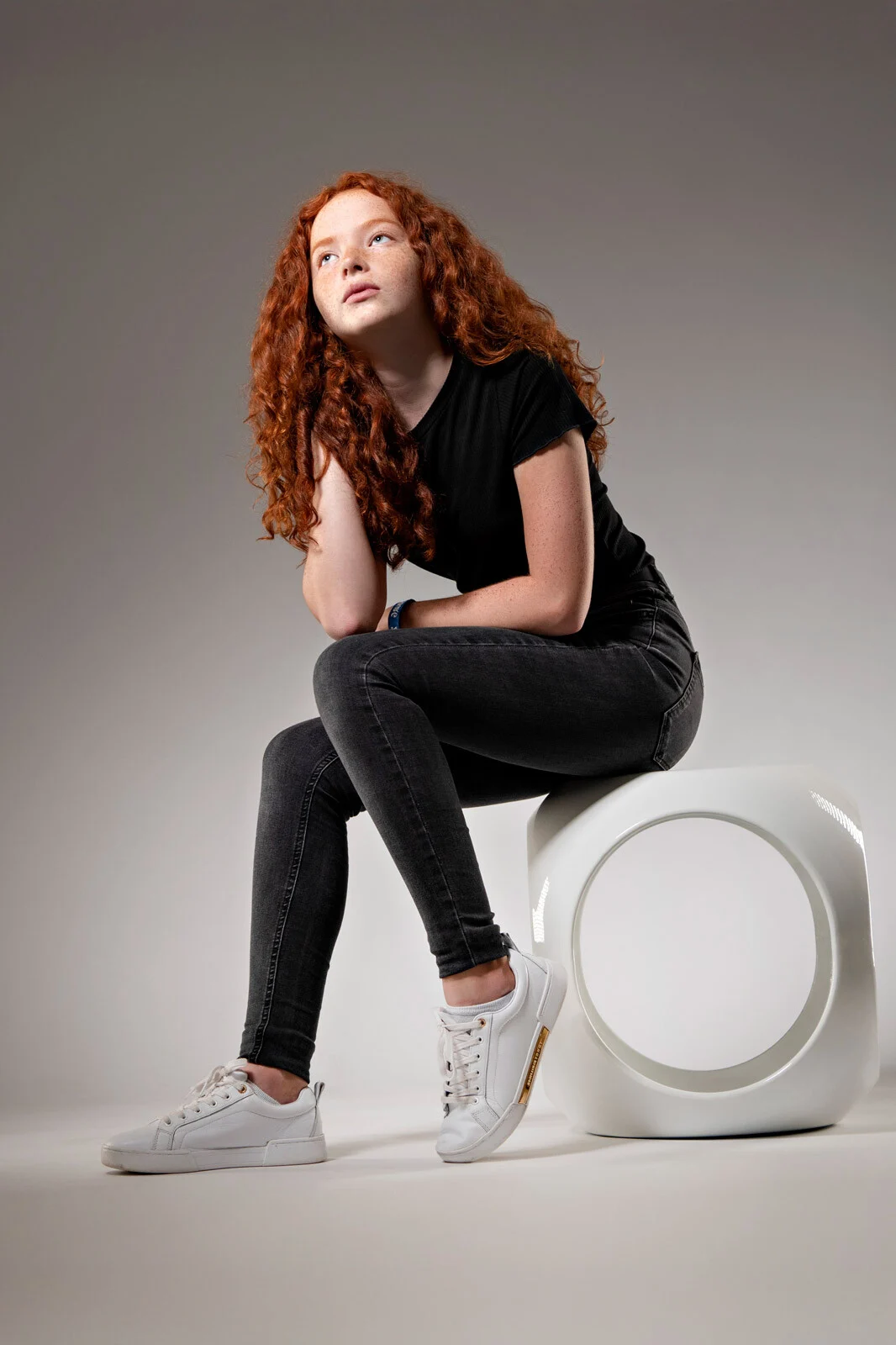 portrait fotos fotostudio marburg | Peter Lauritis Photography Portraitfotos im Fotostudio: junge Frau mit roten Locken sitzt lässig auf einem weißen Hocker