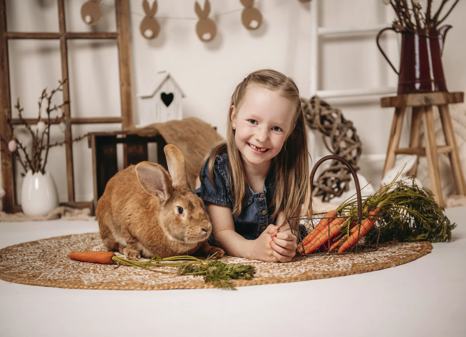 Frühlingshafte Kinderfotos: Mädchen liegt neben einem braunen Hasen auf einem Juteteppich