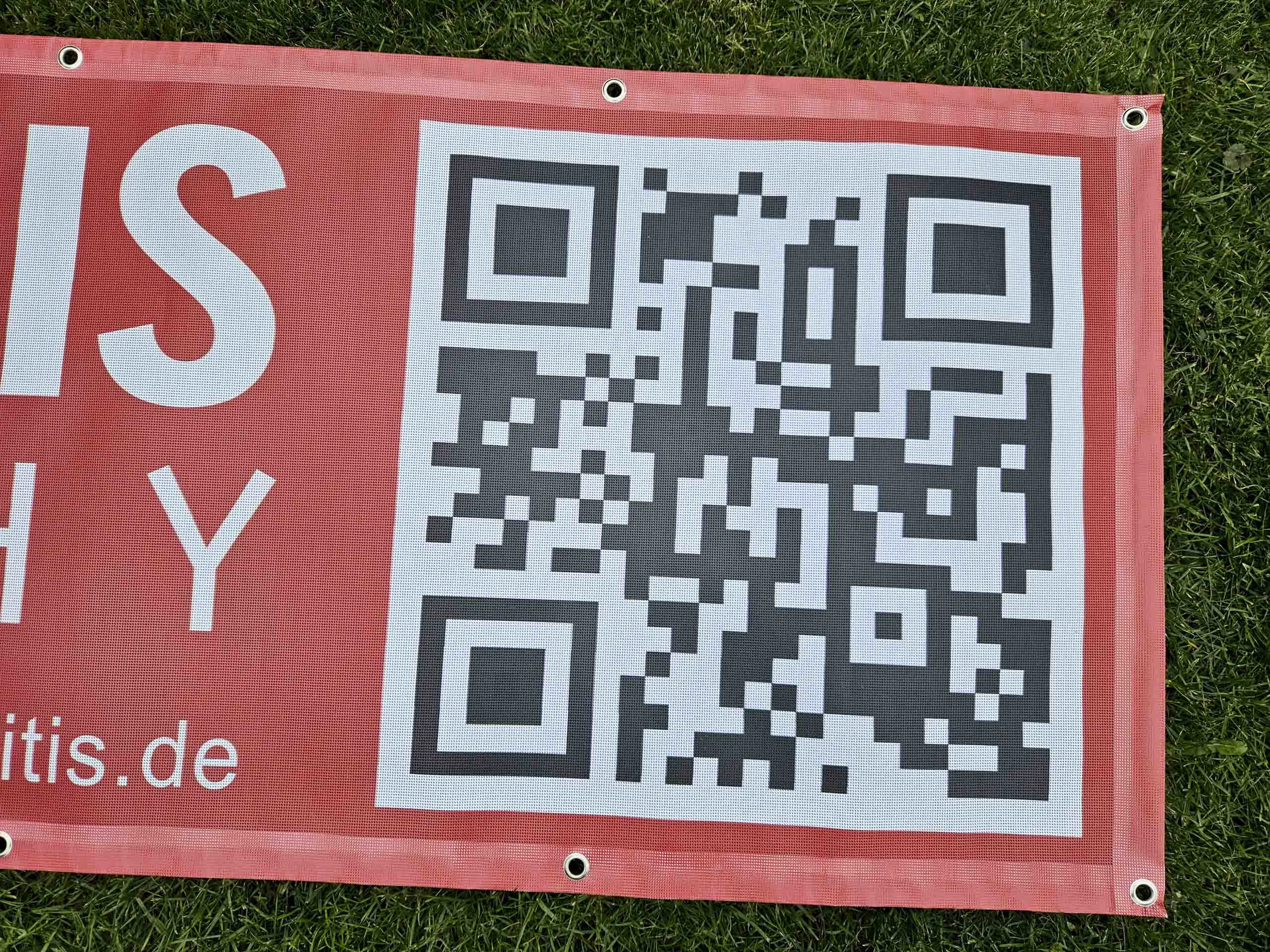 Nahaufnahme des QR-Codes und der Webadresse auf einem roten Werbebanner
