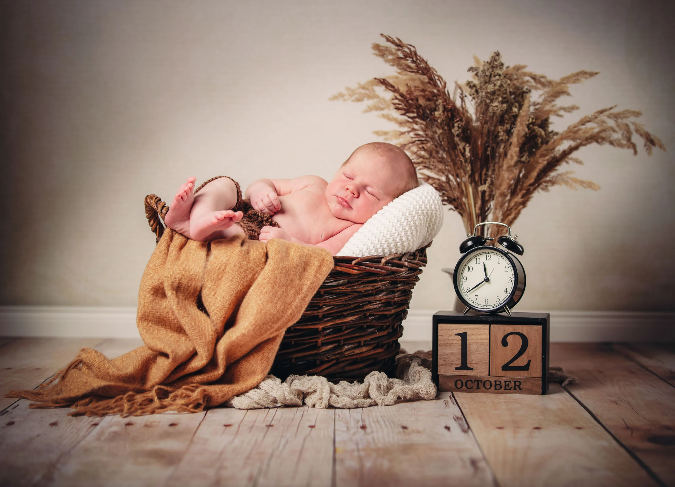 Babyfotos Neugeborene Fotogalerie 007 | Peter Lauritis Photography Schlafendes Neugeborenes im Korb, daneben Wecker und Datumswürfel