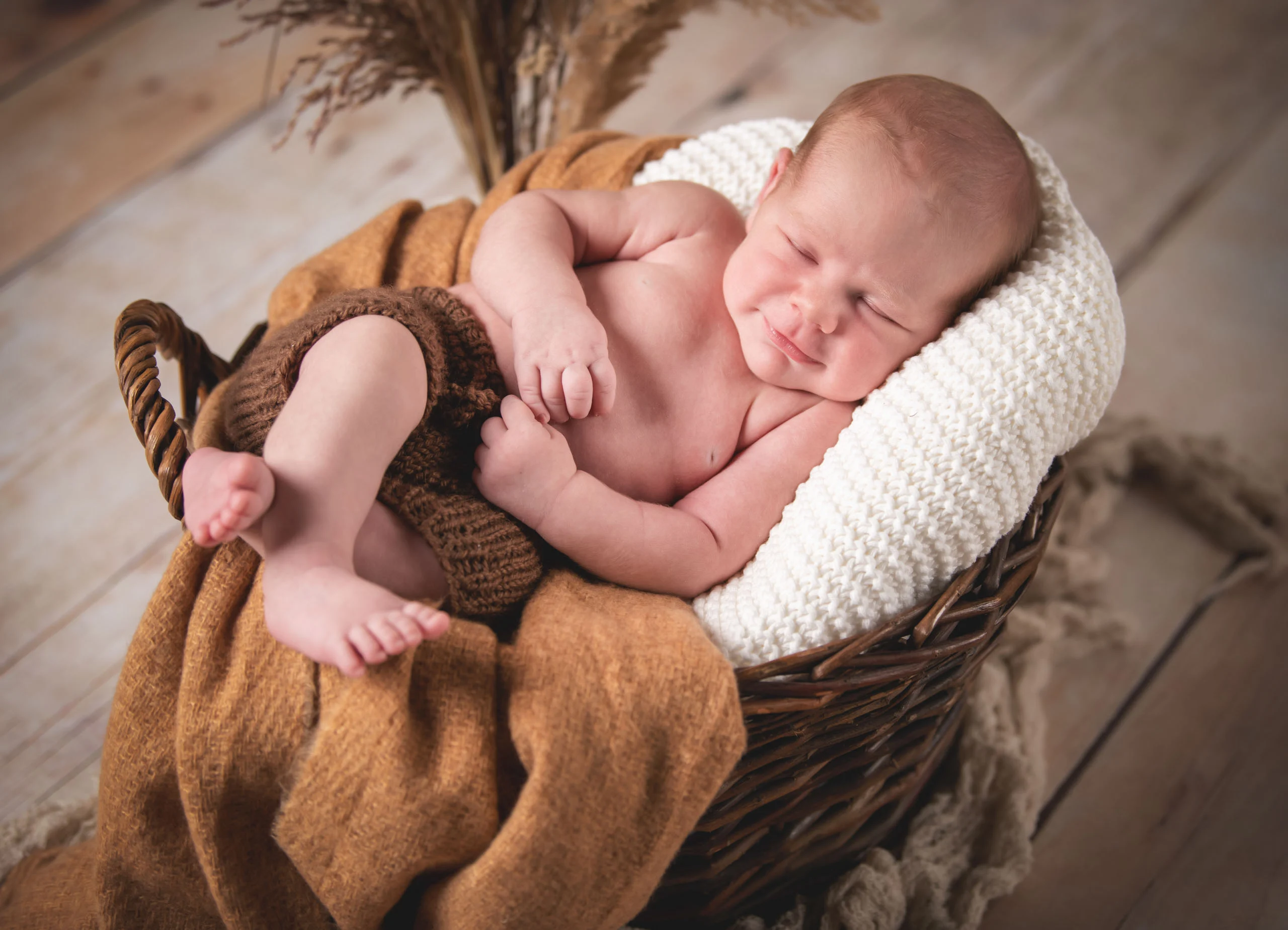 Babyfotos Neugeborene Fotogalerie 008 | Peter Lauritis Photography Schlafendes Neugeborenes liegt auf dem Bauch in einem Korb mit Strickdecke