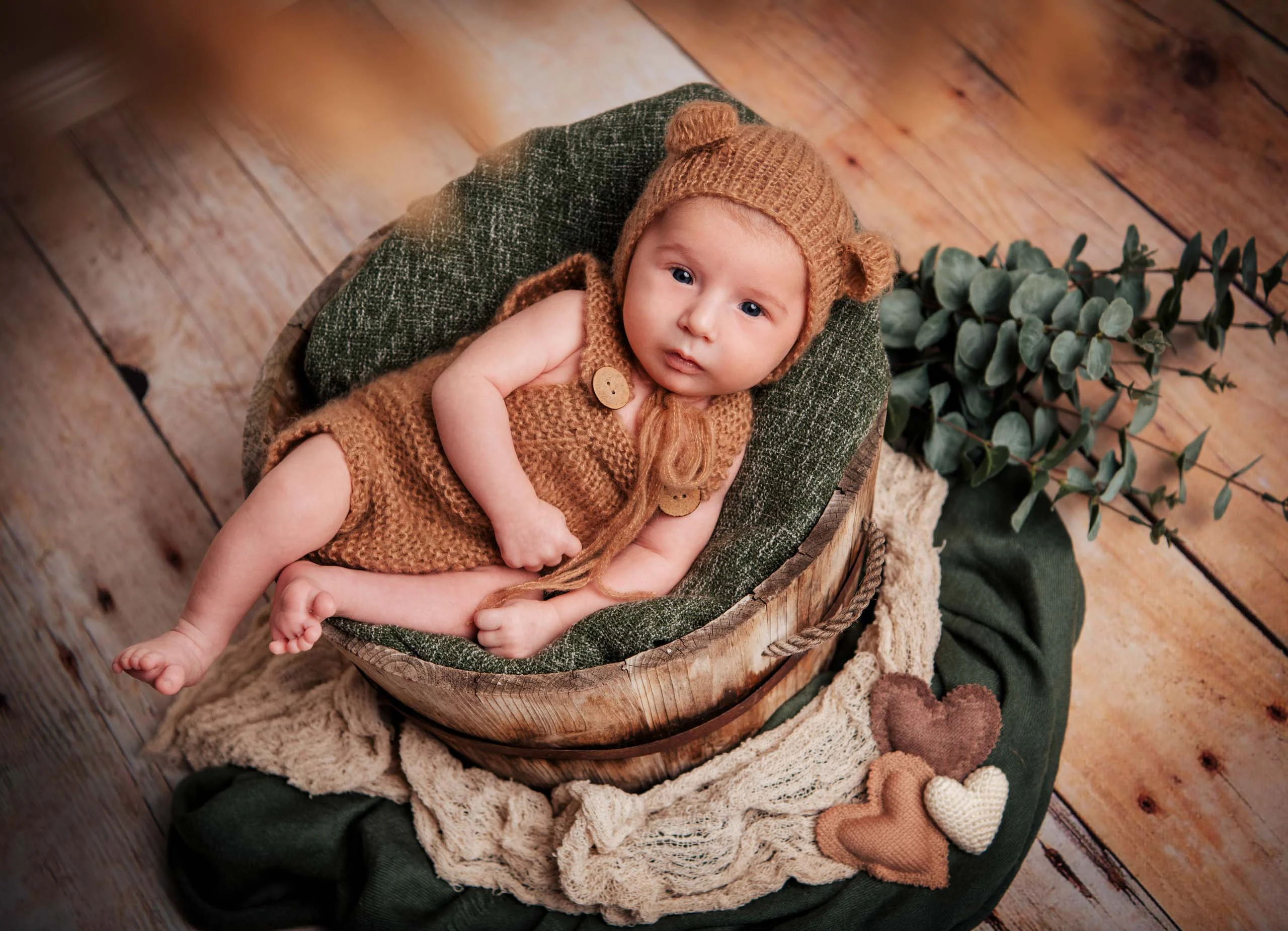 Babyfotos Neugeborene Fotogalerie 010 | Peter Lauritis Photography Baby im gestrickten Bärenanzug schaut aus einer Holzschale in die Kamera