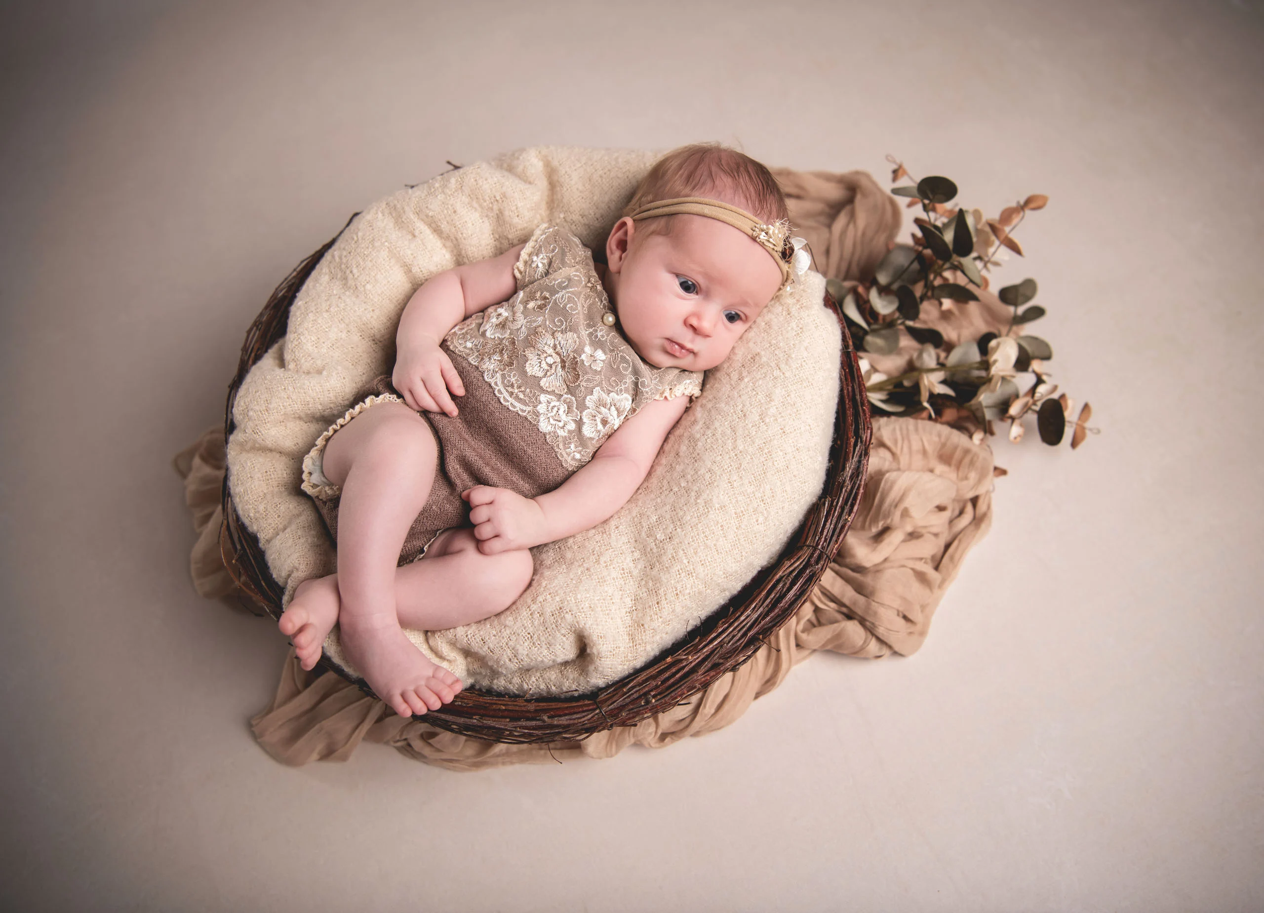 Babyfotos Neugeborene Fotogalerie 020 | Peter Lauritis Photography Baby im Spitzenbody liegt in einem runden Korb, von oben fotografiert