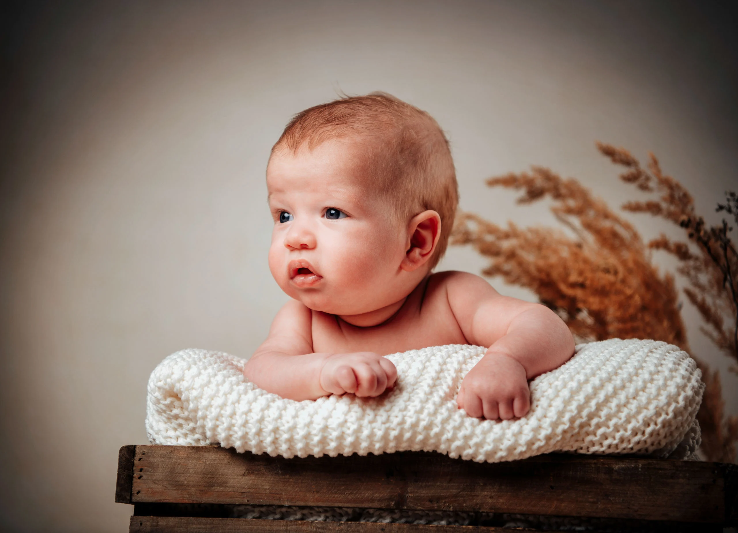 Babyfotos Neugeborene Fotogalerie 027 | Peter Lauritis Photography Baby stützt sich auf eine Strickdecke und blickt zur Seite