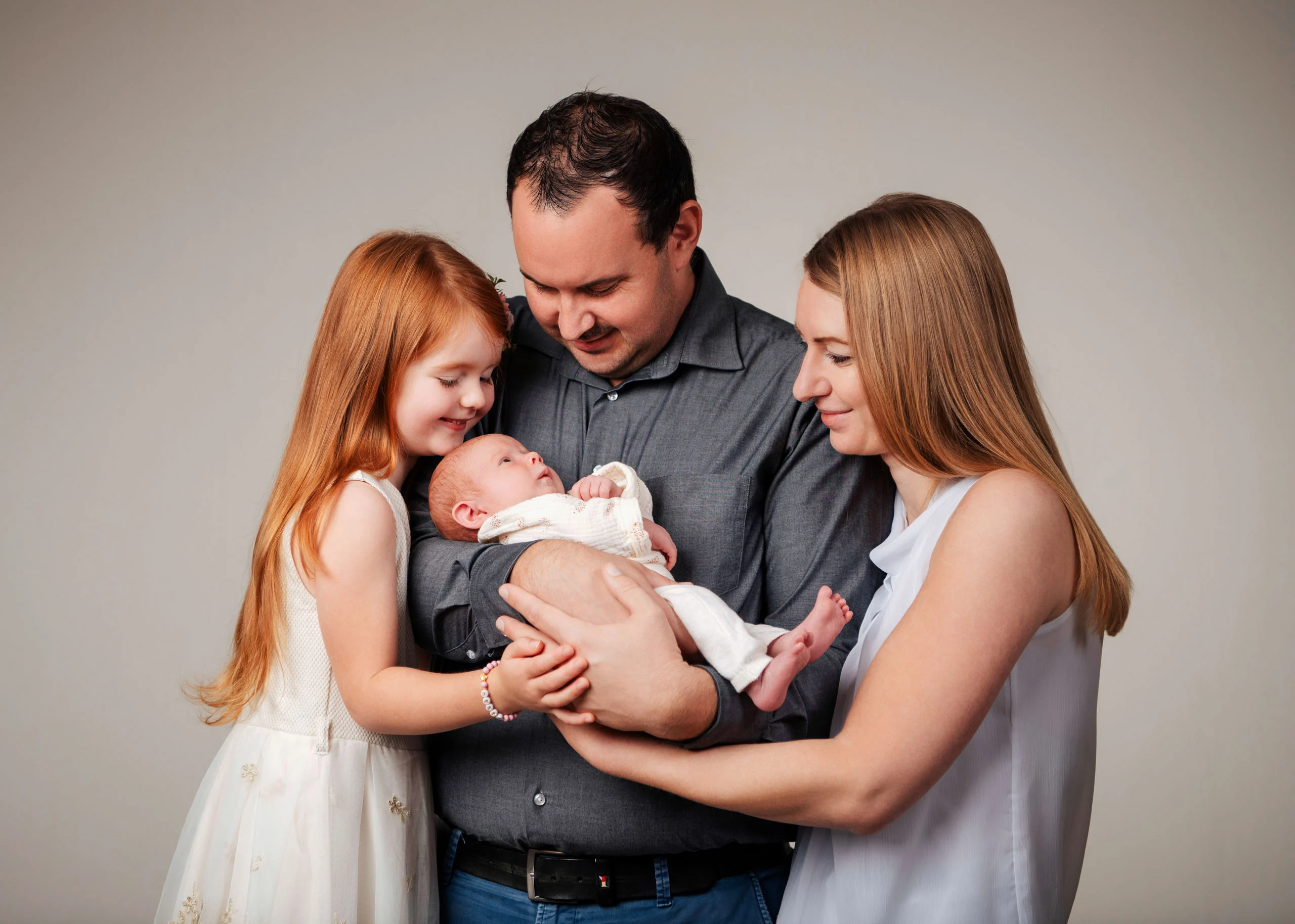 Babyfotos Neugeborene Fotogalerie 035 | Peter Lauritis Photography Familie mit Tochter beugt sich über das Neugeborene im Arm des Vaters