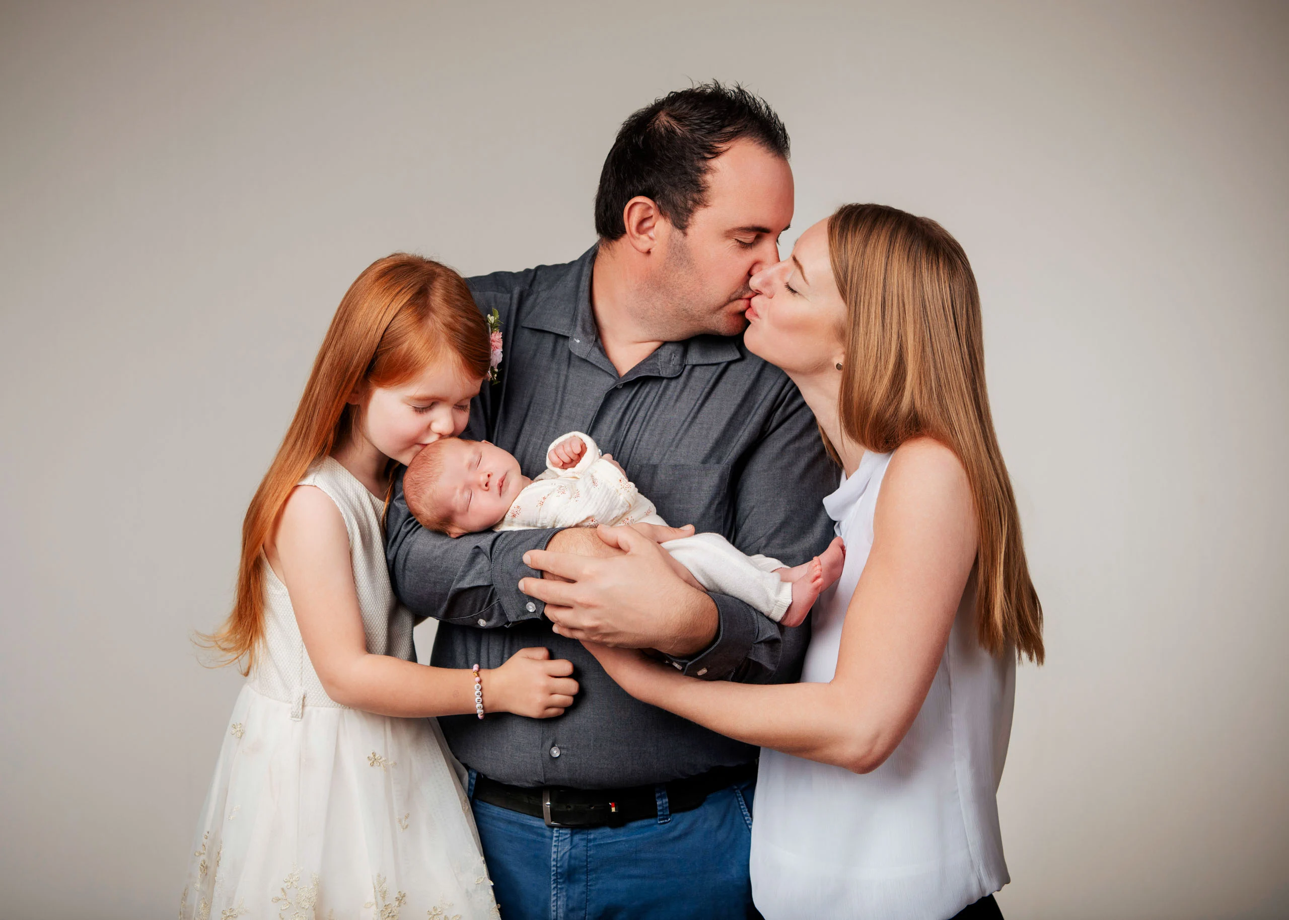 Babyfotos Neugeborene Fotogalerie 036 | Peter Lauritis Photography Eltern küssen sich, die rothaarige Tochter küsst das Baby