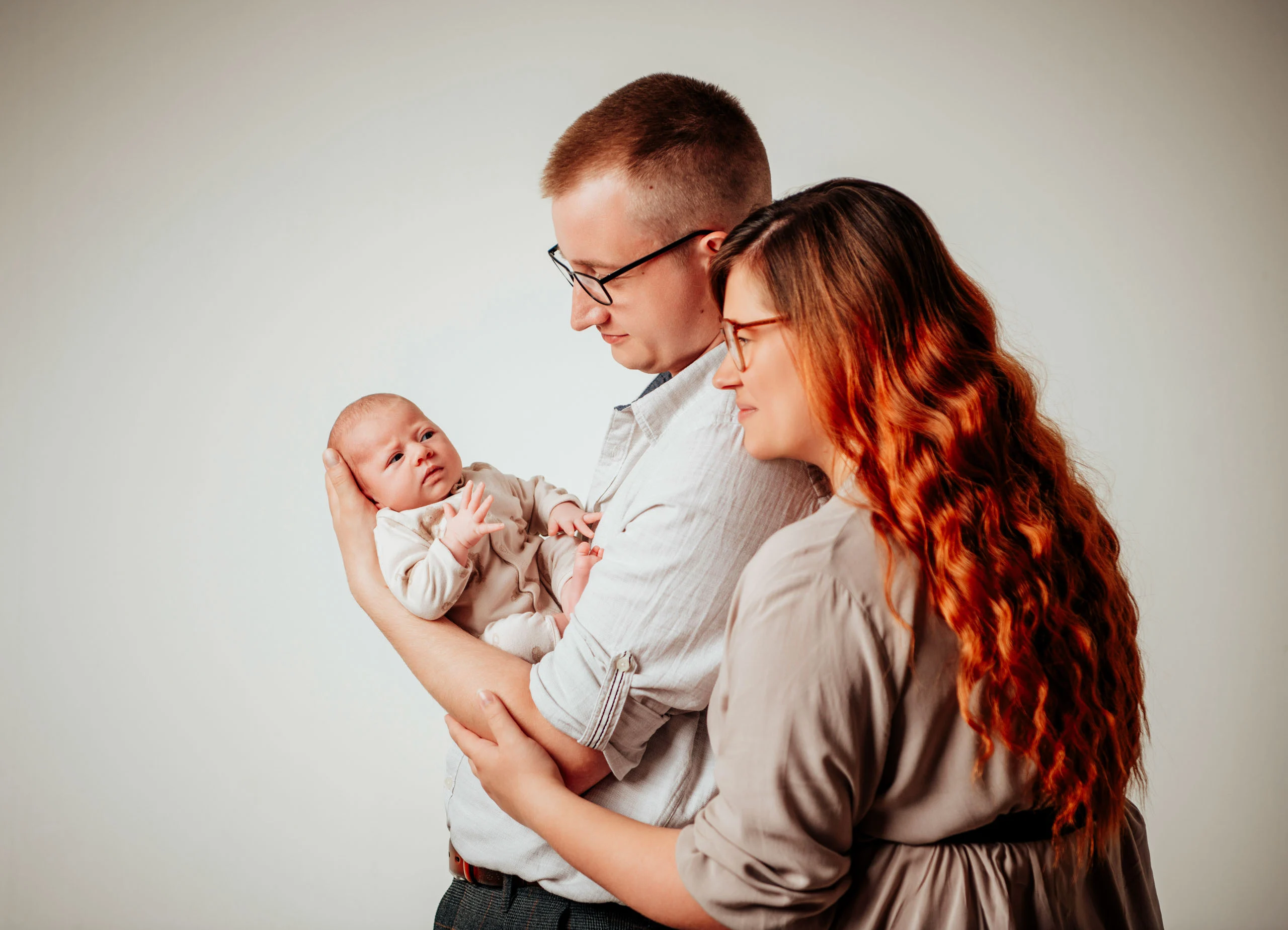 Babyfotos Neugeborene Fotogalerie 048 | Peter Lauritis Photography Mann hält das Neugeborene, die rothaarige Frau lehnt sich an seine Schulter