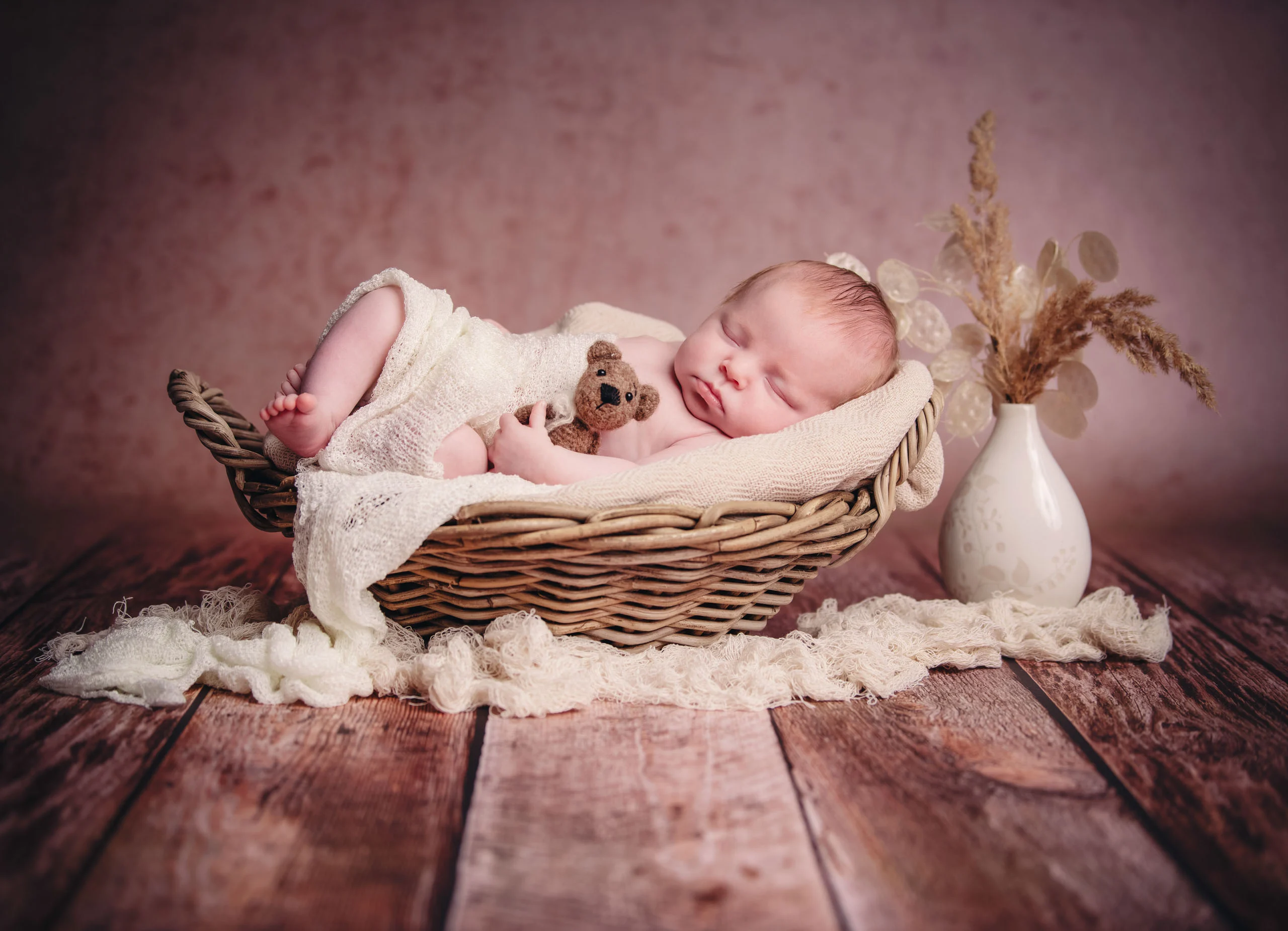 Babyfotos Neugeborene Fotogalerie 049 | Peter Lauritis Photography Schlafendes Neugeborenes mit Teddy im Weidenkorb auf Holzboden