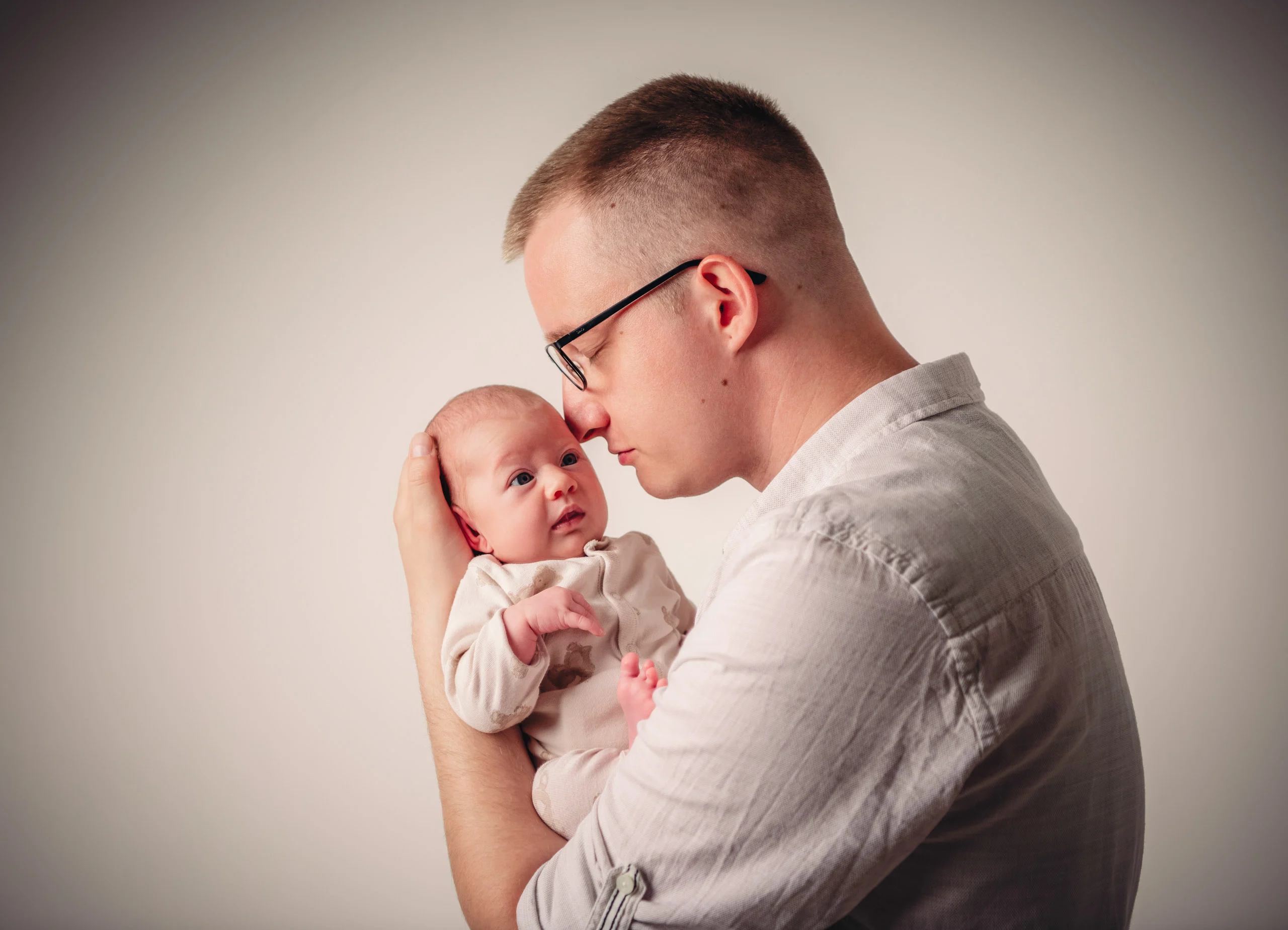 Babyfotos Neugeborene Fotogalerie 052 | Peter Lauritis Photography Mann mit Brille hält das Neugeborene nah an sein Gesicht