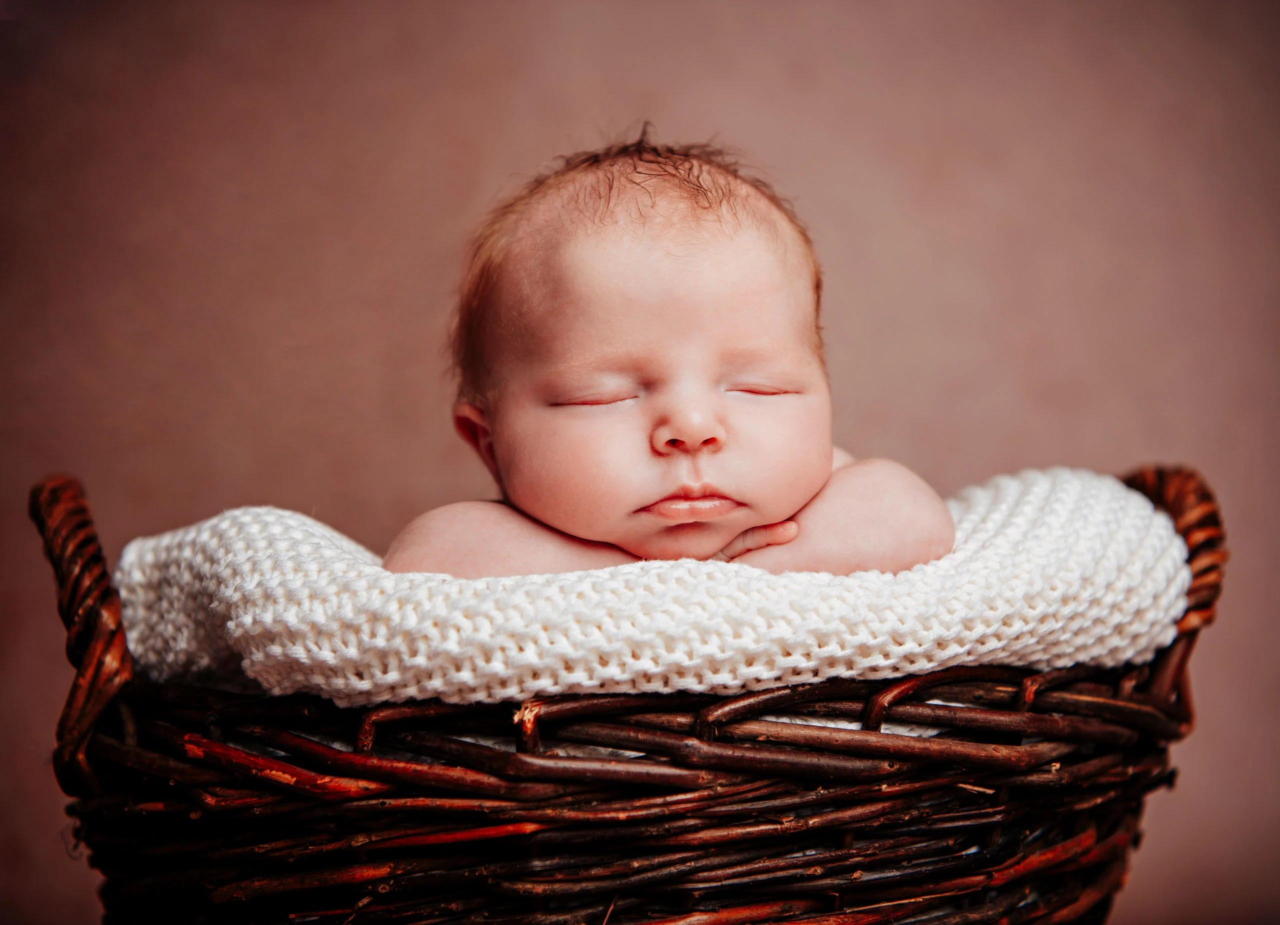 Babyfotos Neugeborene Fotogalerie 057 | Peter Lauritis Photography Neugeborenes stützt das Kinn auf eine Strickdecke im Korb