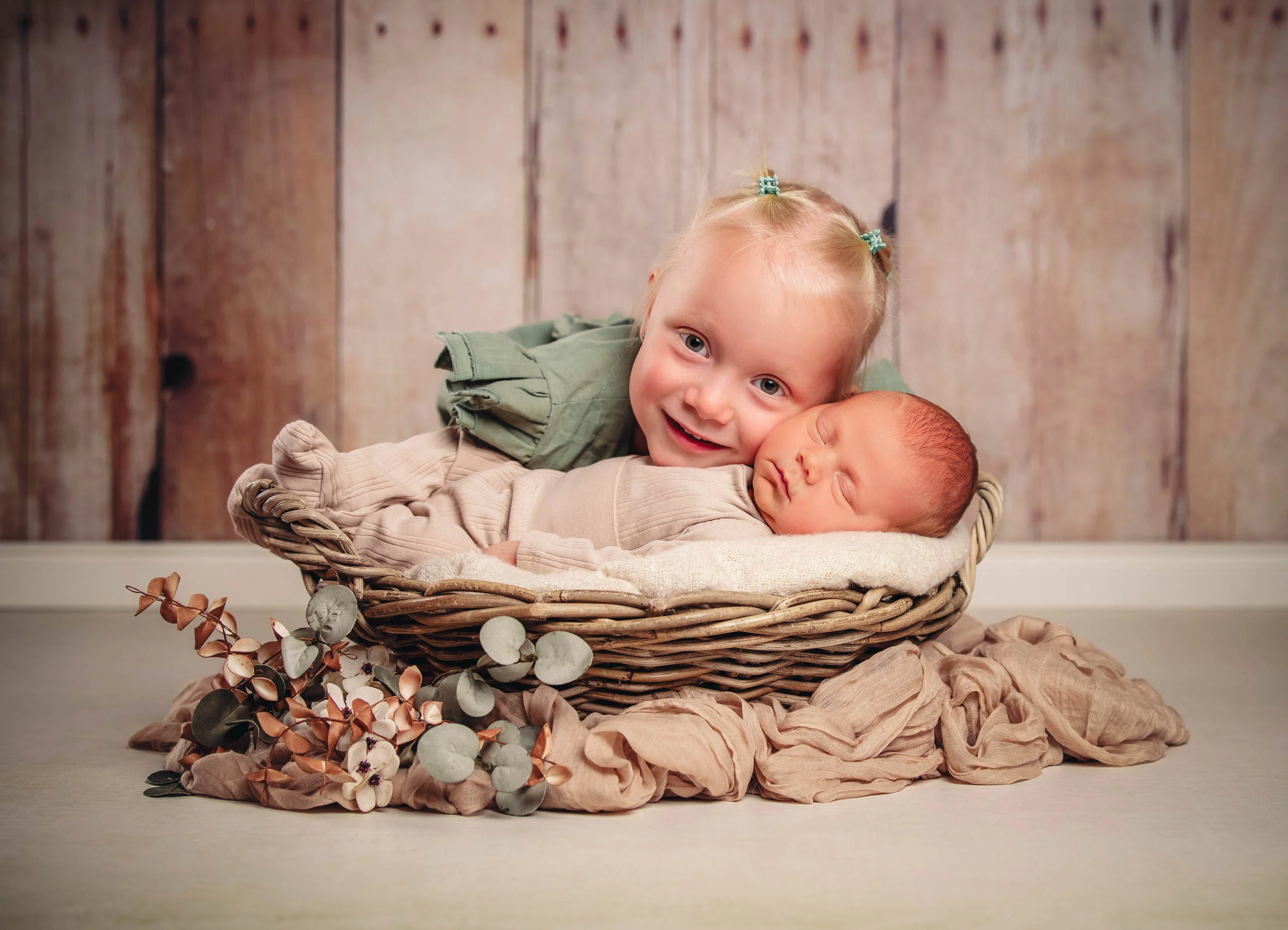 Babyfotos Neugeborene Fotogalerie 060 | Peter Lauritis Photography Lachendes Kleinkind lehnt den Kopf an das schlafende Neugeborene im Korb