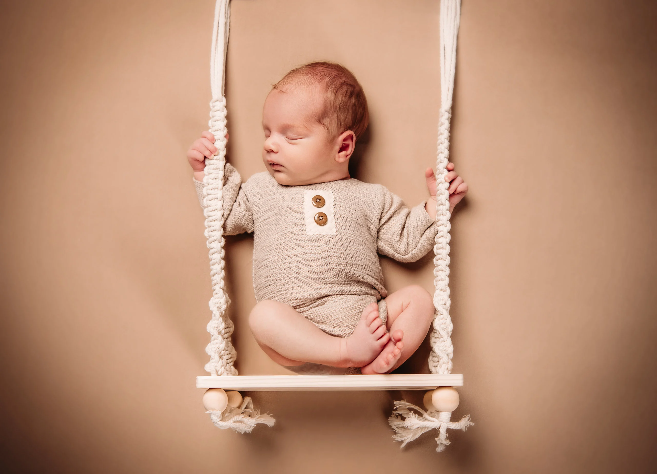 Babyfotos Neugeborene Fotogalerie 065 | Peter Lauritis Photography Schlafendes Neugeborenes im Strickanzug auf einer Makramee-Schaukel