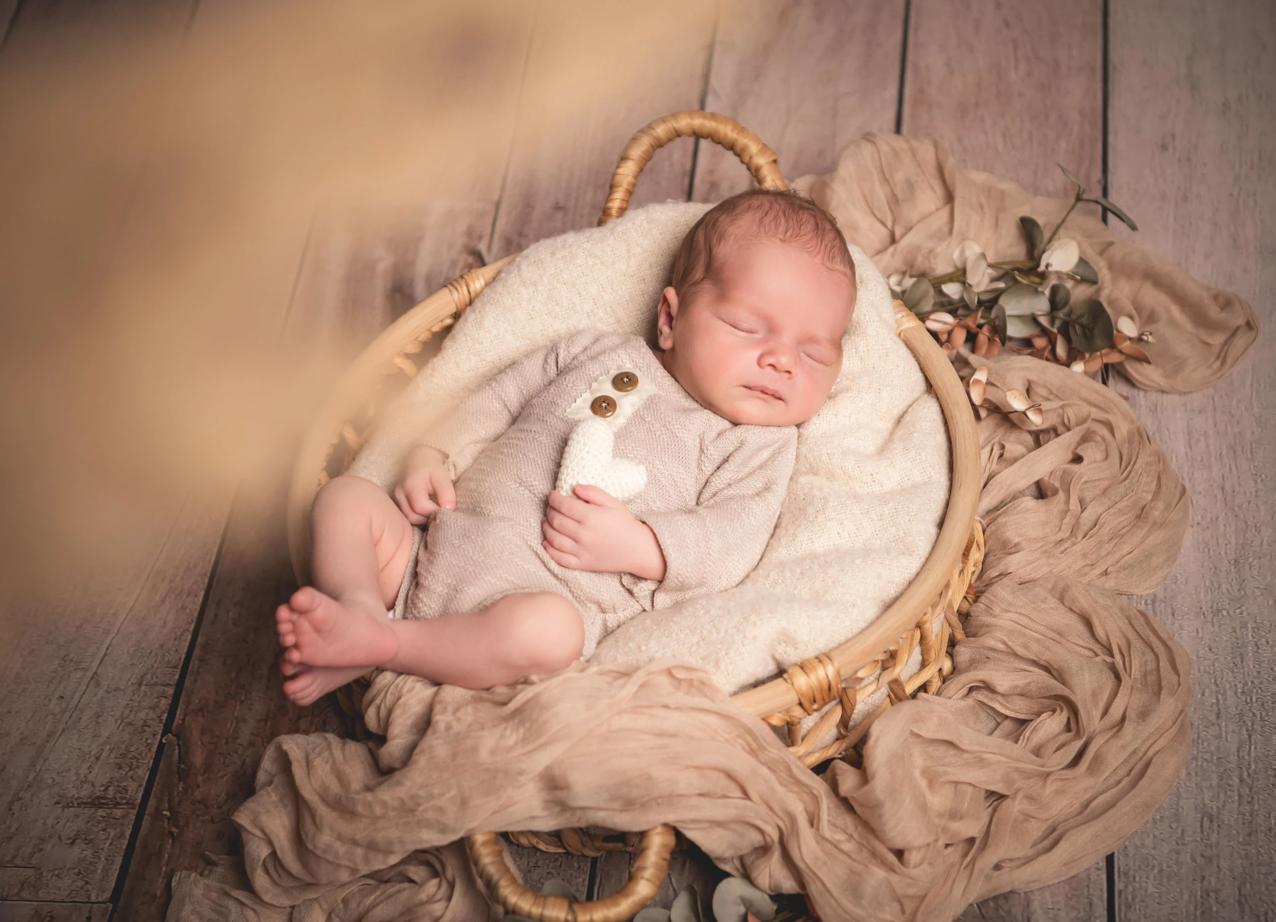Babyfotos Neugeborene Fotogalerie 067 | Peter Lauritis Photography Schlafendes Neugeborenes in einem runden Rattankorb auf Holzboden