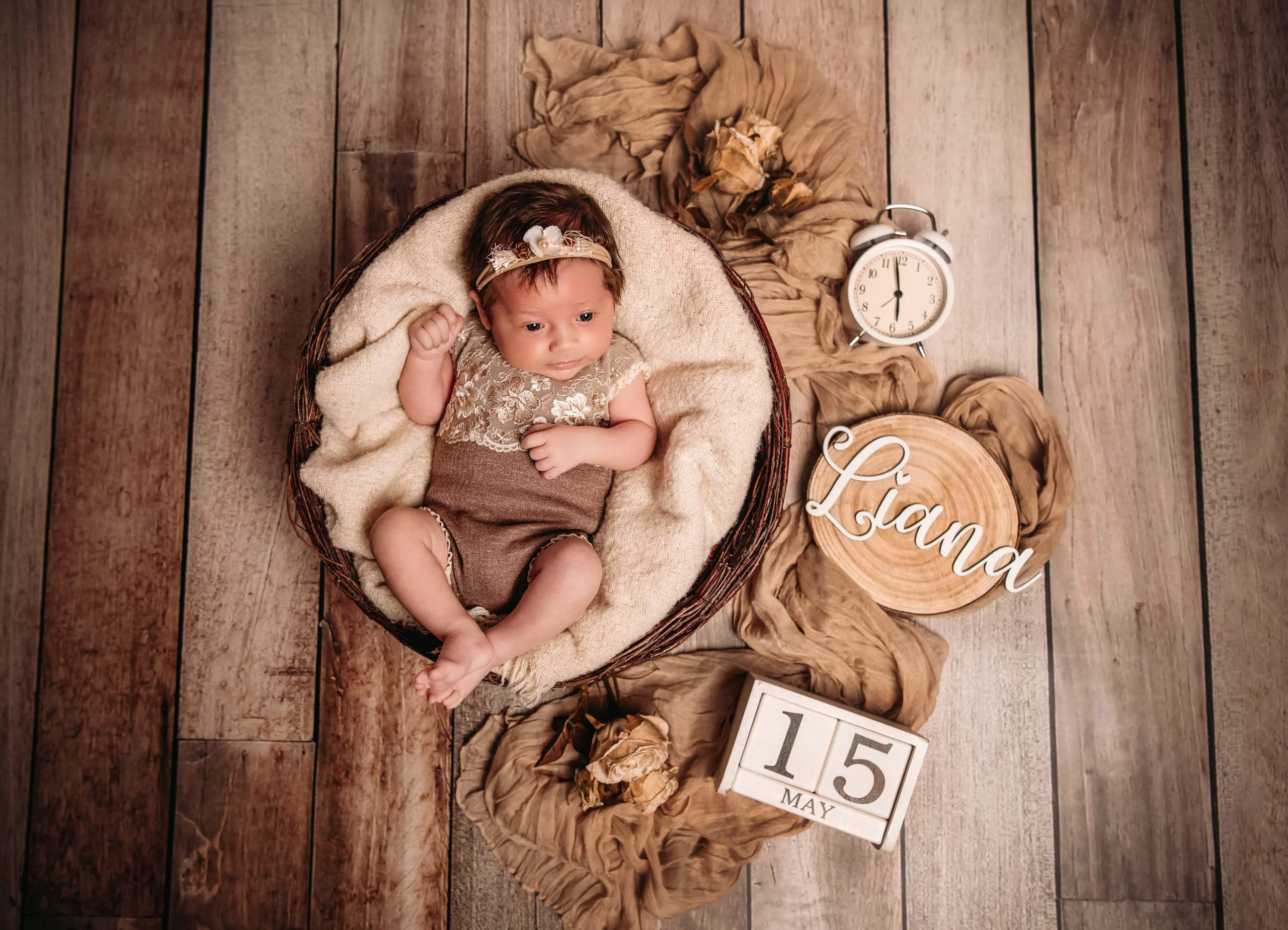 Babyfotos Neugeborene Fotogalerie 071 | Peter Lauritis Photography Baby im Korb auf Holzboden, daneben Wecker, Namensschild und Datumswürfel