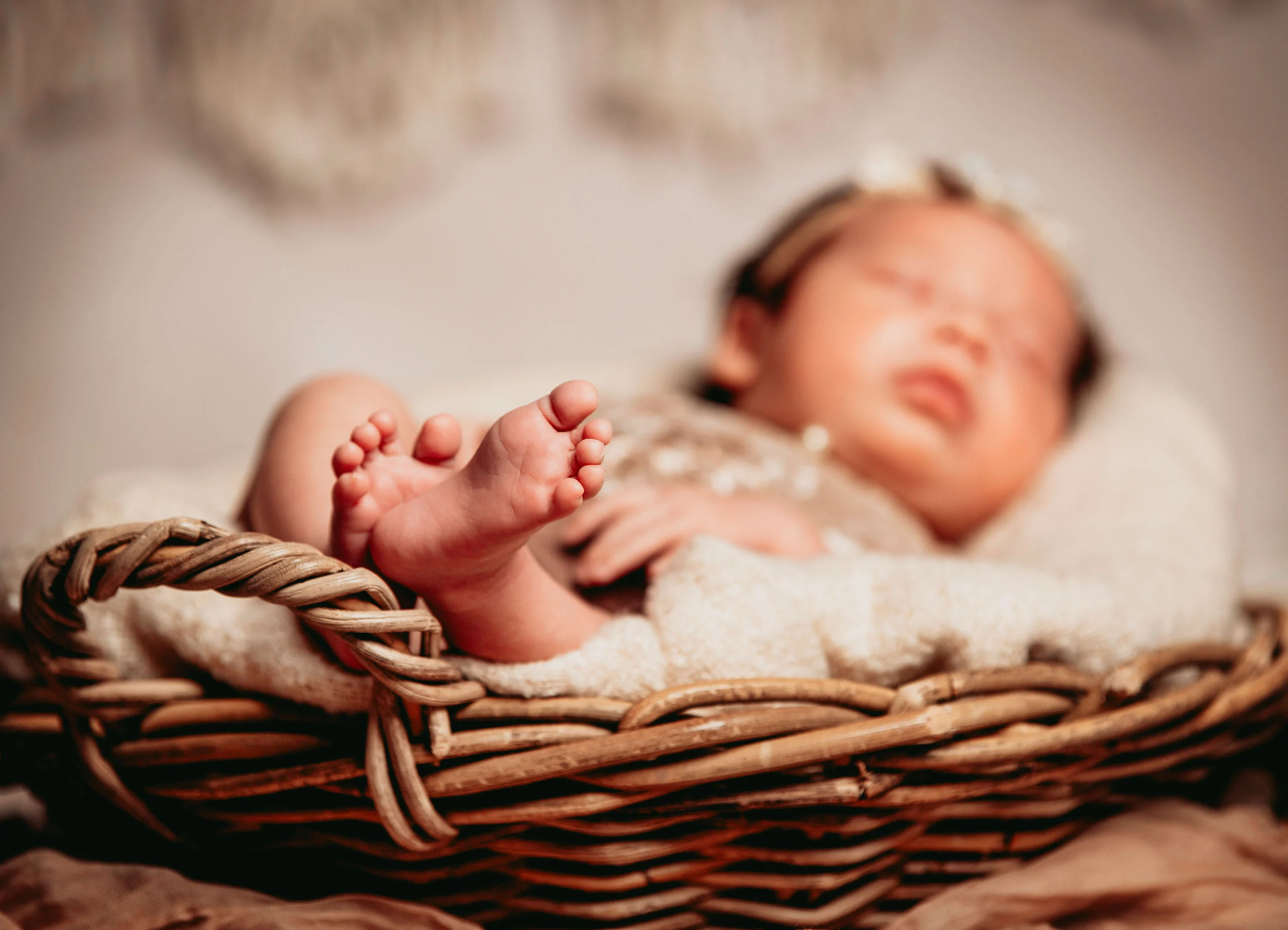 Babyfotos Neugeborene Fotogalerie 076 | Peter Lauritis Photography Babyfüße im Vordergrund, dahinter unscharf das schlafende Neugeborene im Korb