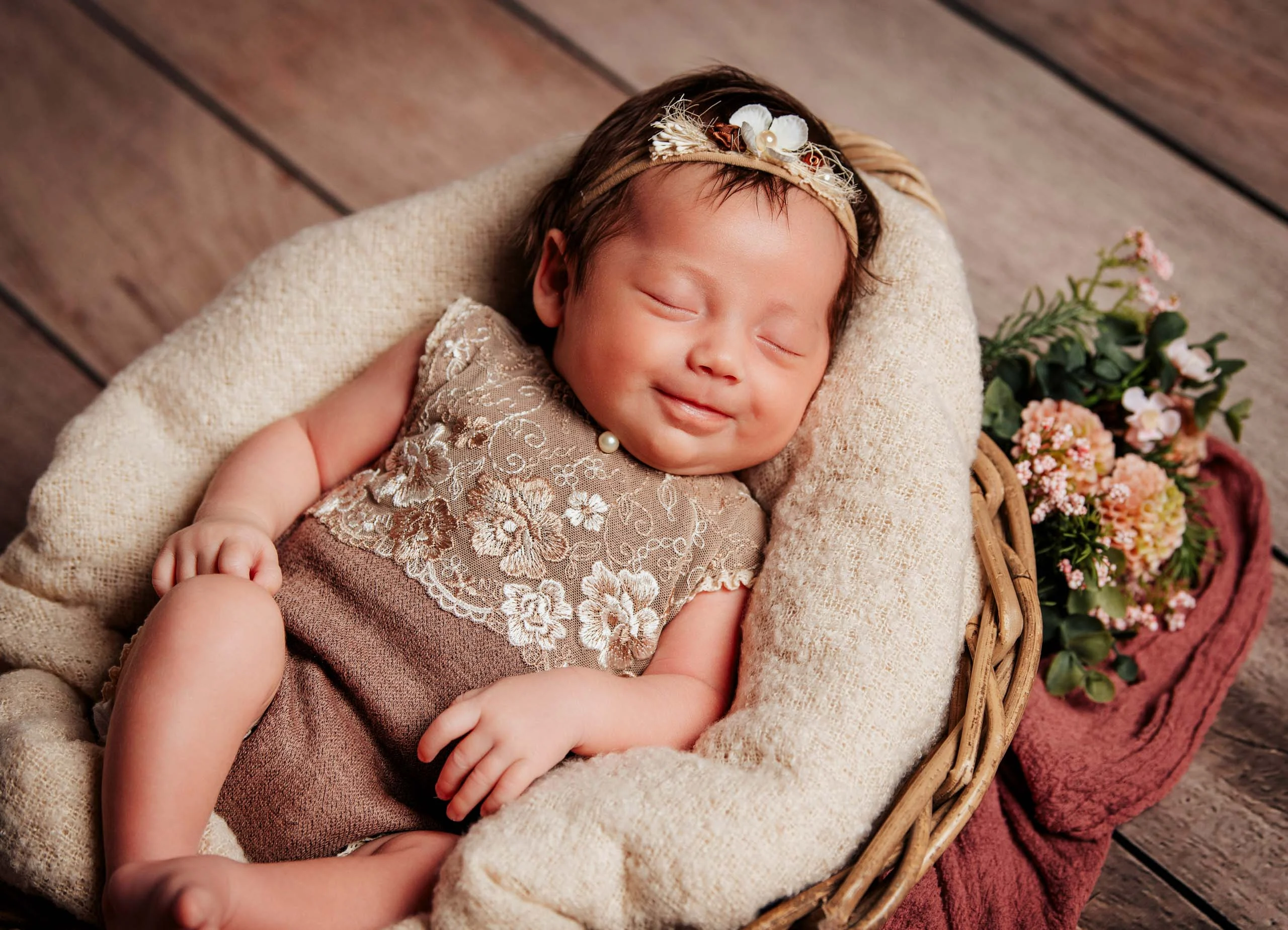 Babyfotos Neugeborene Fotogalerie 077 | Peter Lauritis Photography Lächelnd schlafendes Neugeborenes im Spitzenbody im Korb mit Blumen