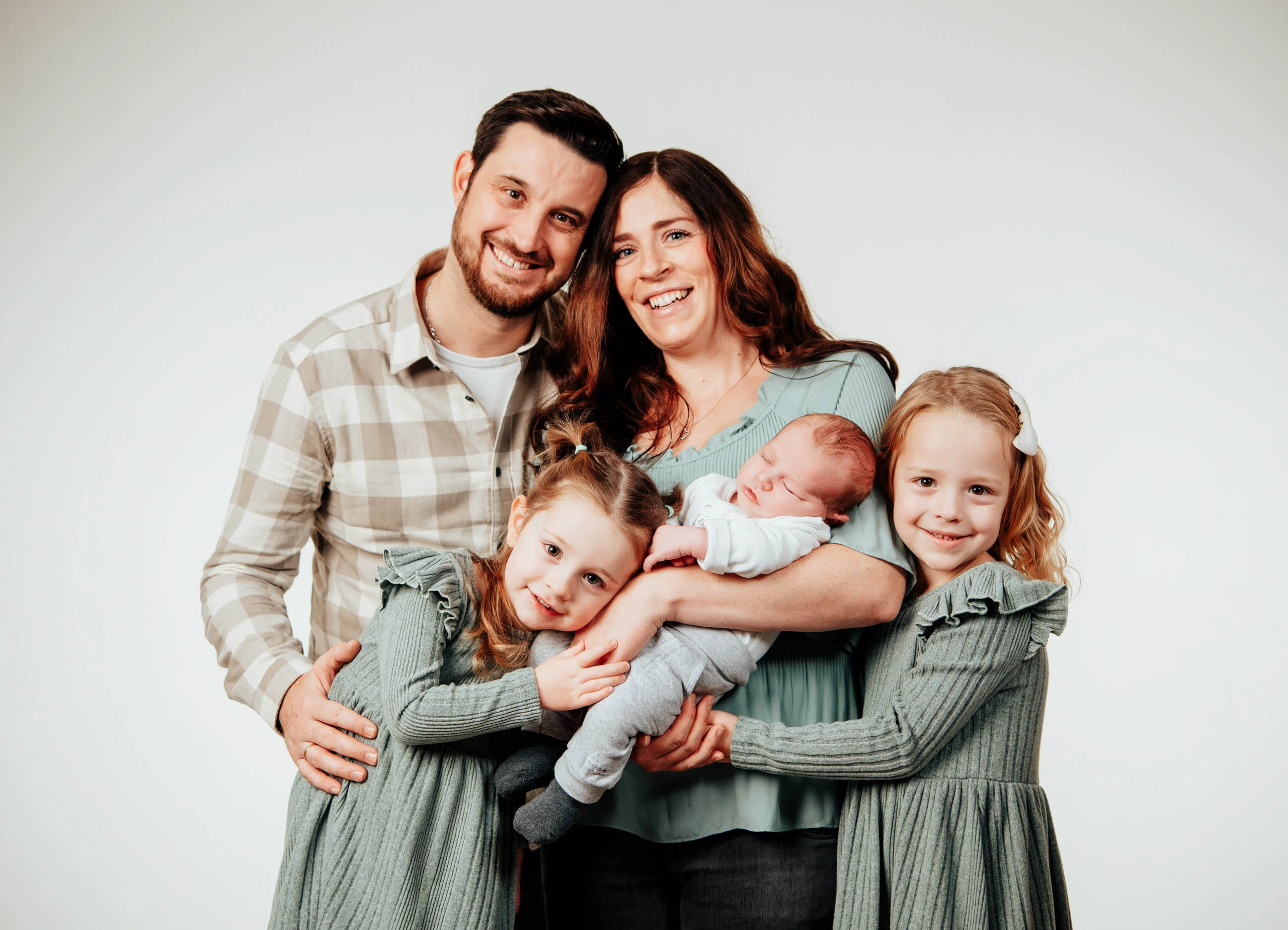 Babyfotos Neugeborene Fotogalerie 081 | Peter Lauritis Photography Familie mit zwei Mädchen in Salbeigrün hält lachend das Neugeborene