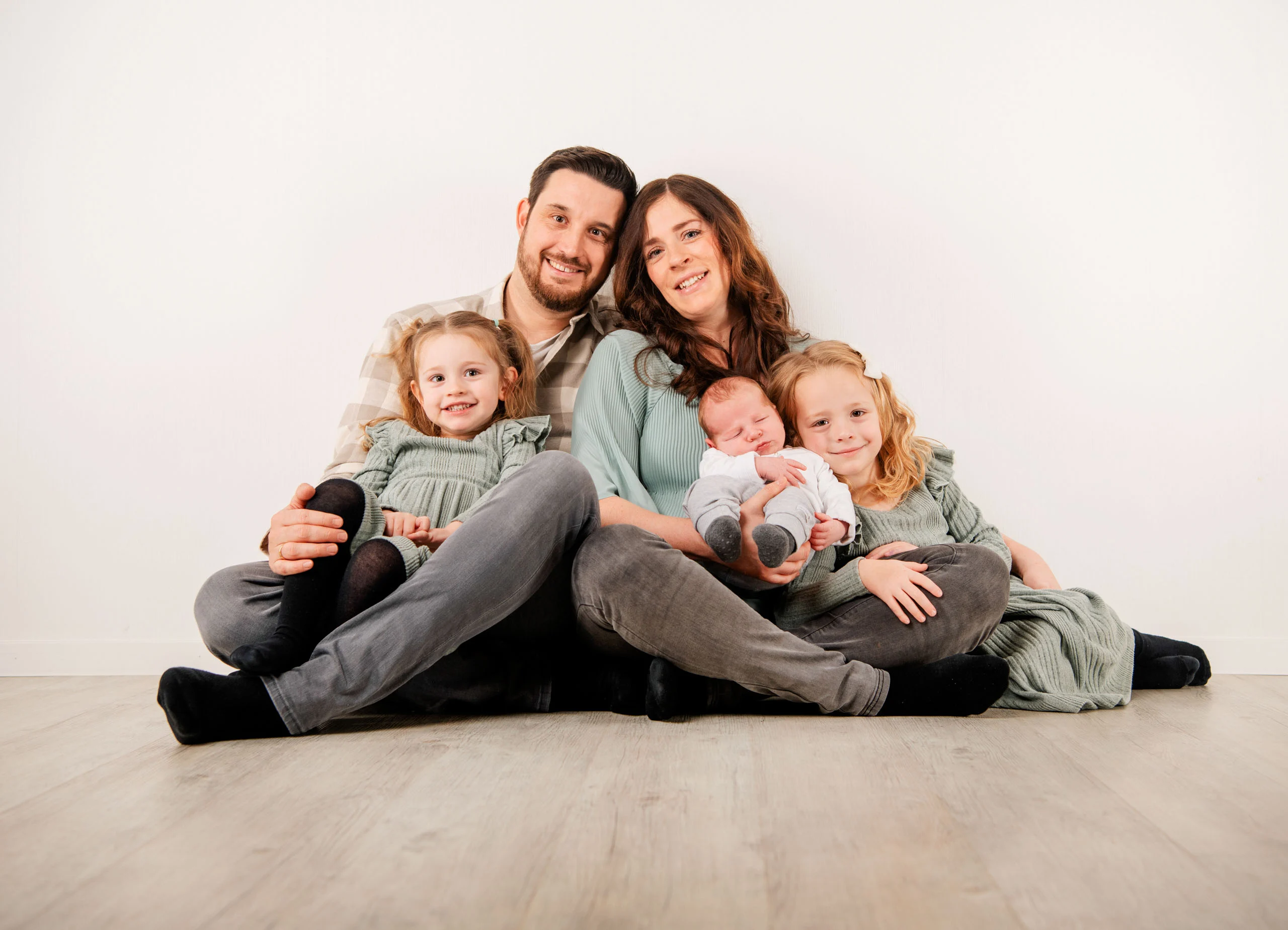 Babyfotos Neugeborene Fotogalerie 082 | Peter Lauritis Photography Familie mit zwei Mädchen sitzt mit dem Neugeborenen auf dem Studioboden