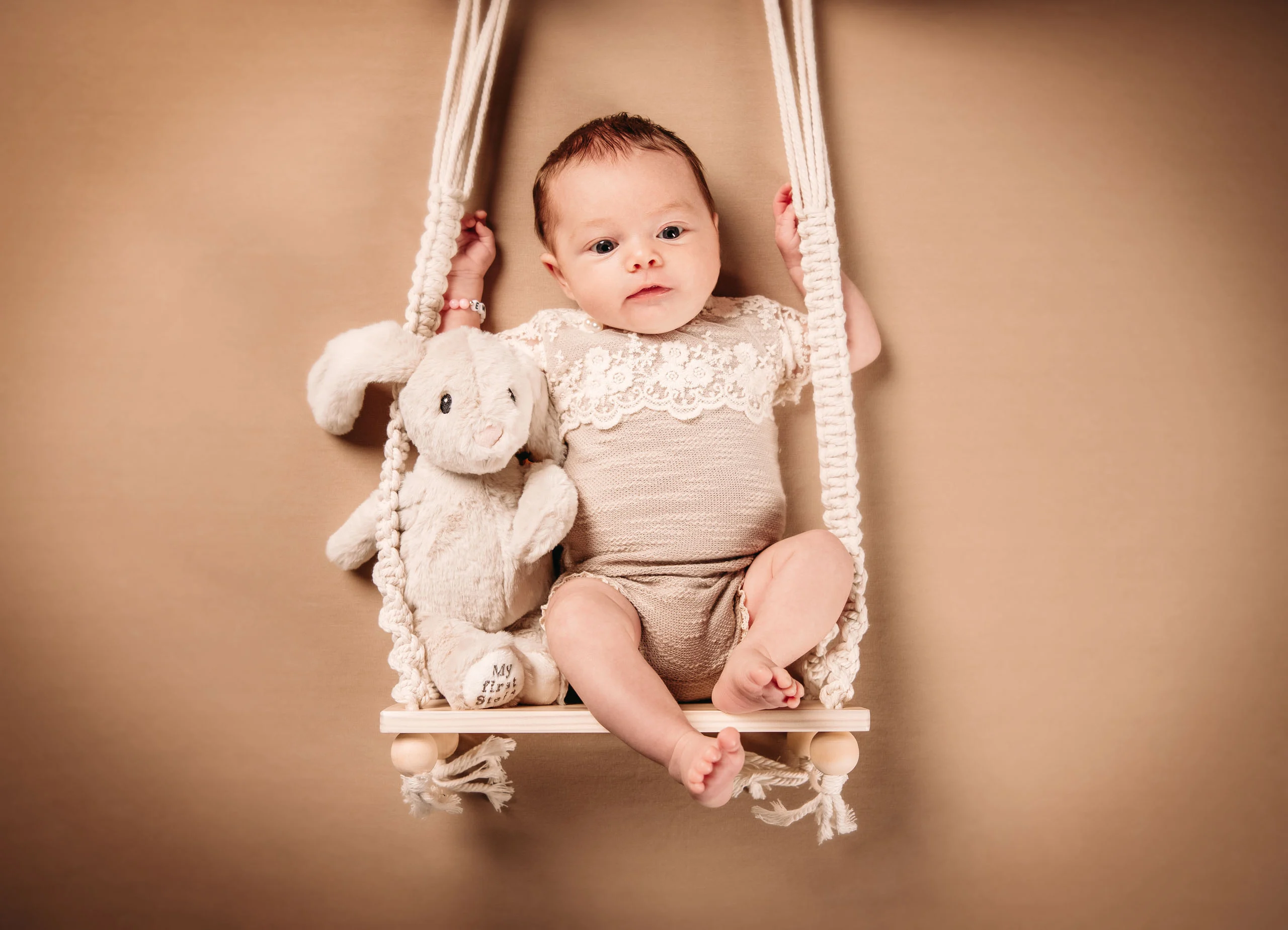 Babyfotos Neugeborene Fotogalerie 083 | Peter Lauritis Photography Baby mit Plüschhasen sitzt auf einer Makramee-Schaukel