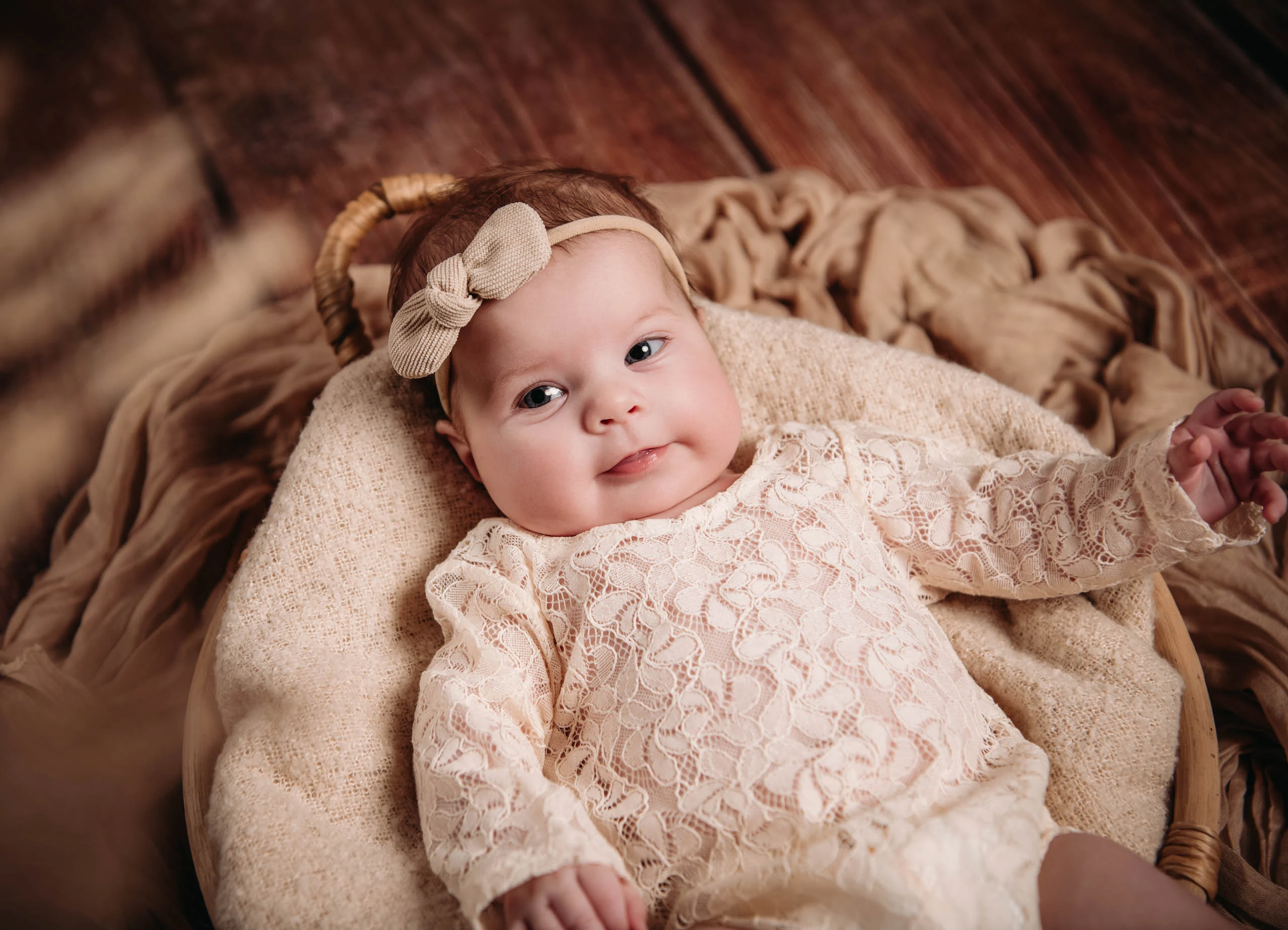 Babyfotos Neugeborene Fotogalerie 087 | Peter Lauritis Photography Baby im Spitzenanzug mit Schleife liegt lächelnd im Korb