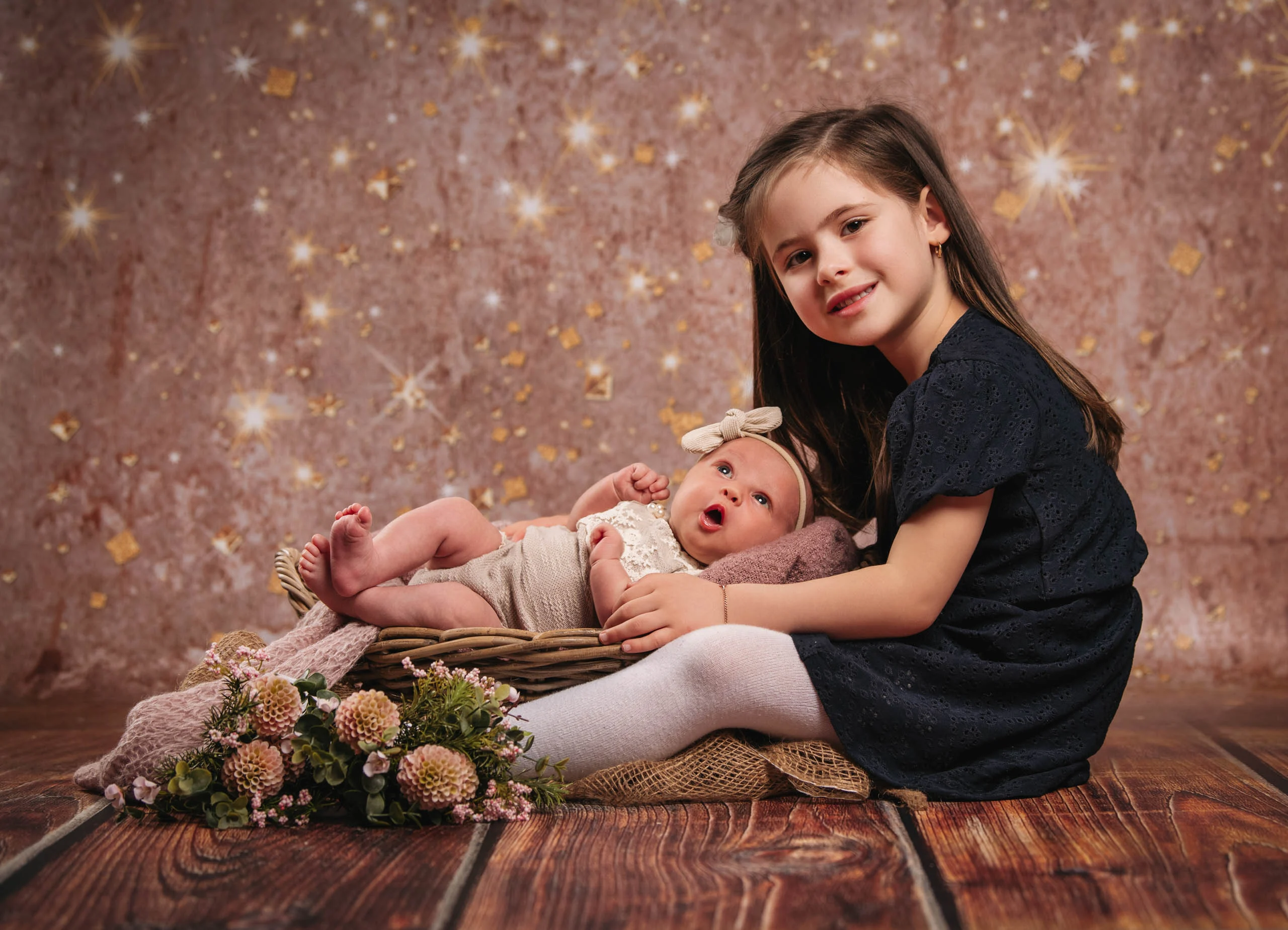 Babyfotos Neugeborene Fotogalerie 092 | Peter Lauritis Photography Mädchen im dunklen Kleid sitzt neben dem Baby im Korb