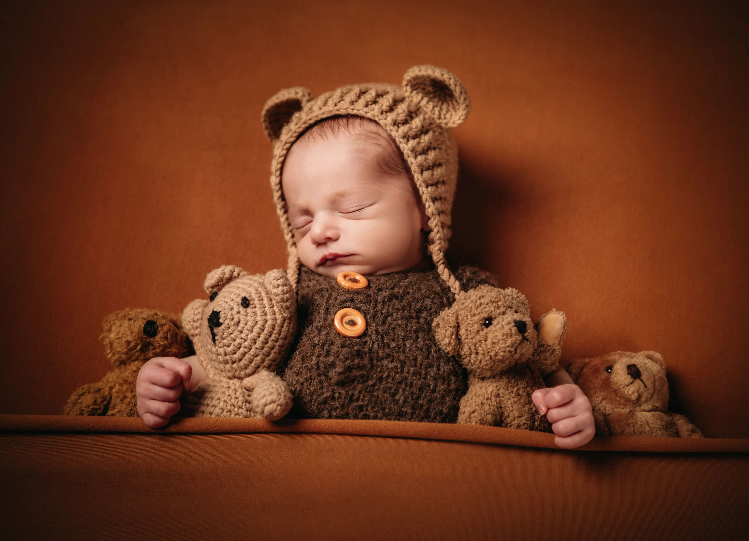 Babyfotos Neugeborene Fotogalerie 094 | Peter Lauritis Photography Schlafendes Neugeborenes in Bärenmütze zwischen gehäkelten Teddys