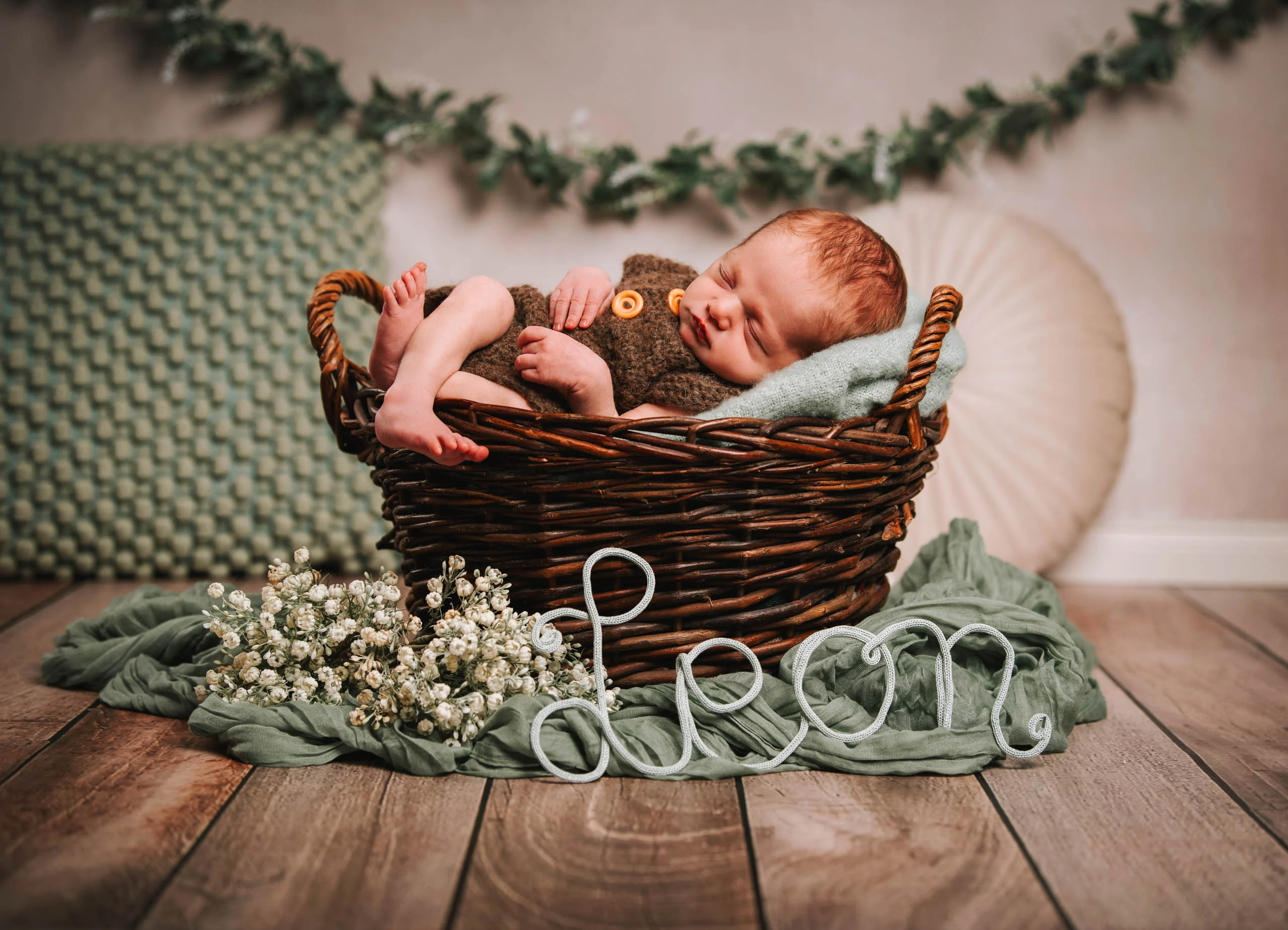 Babyfotos Neugeborene Fotogalerie 095 | Peter Lauritis Photography Schlafendes Neugeborenes im Korb, davor ein Schriftzug aus Draht und Schleierkraut