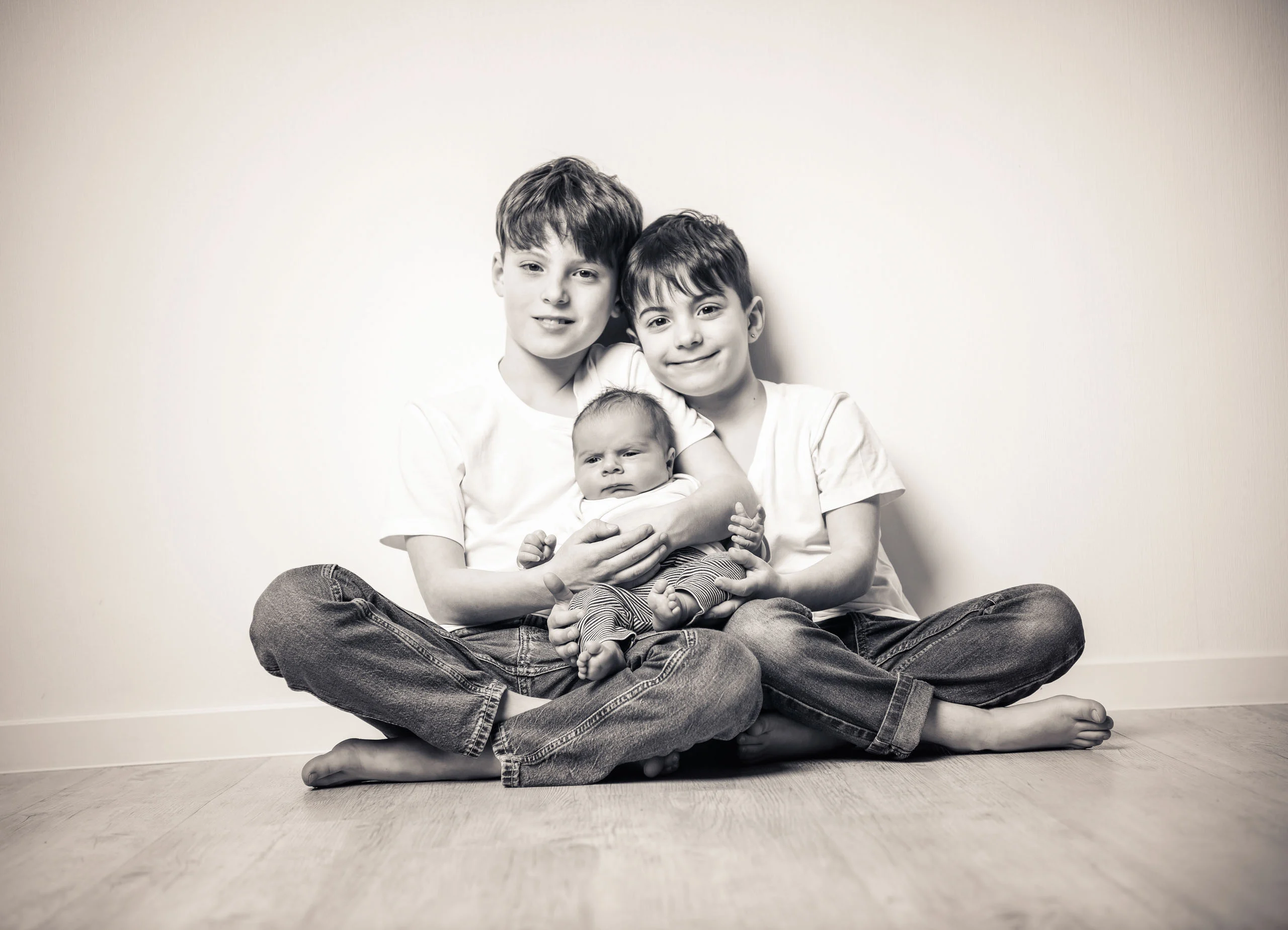 Babyfotos Neugeborene Fotogalerie 108 | Peter Lauritis Photography Zwei Jungen halten das Neugeborene und lächeln in die Kamera
