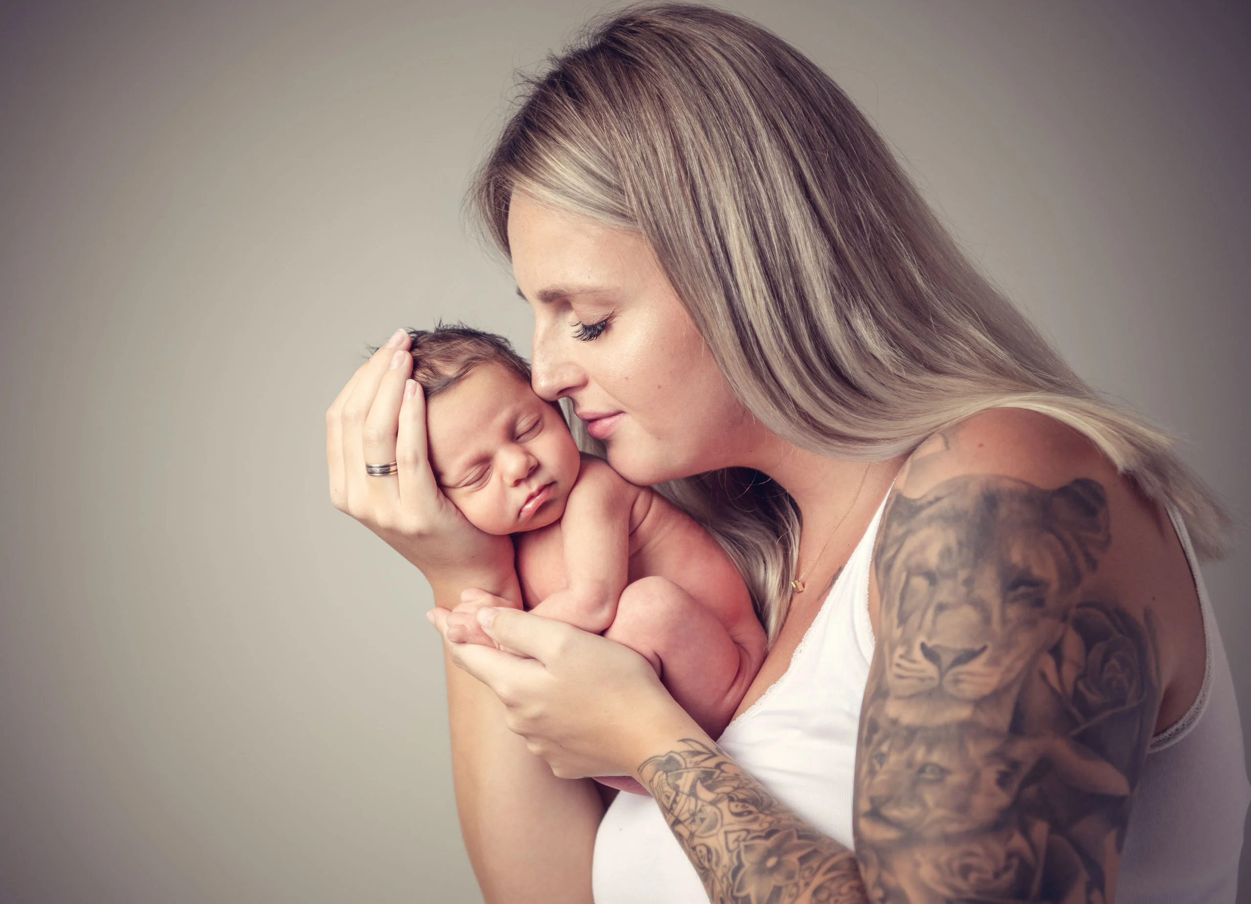 Babyfotos Neugeborene Fotogalerie 109 | Peter Lauritis Photography Tätowierte Frau hält ihr Neugeborenes in den Händen und drückt es an die Wange