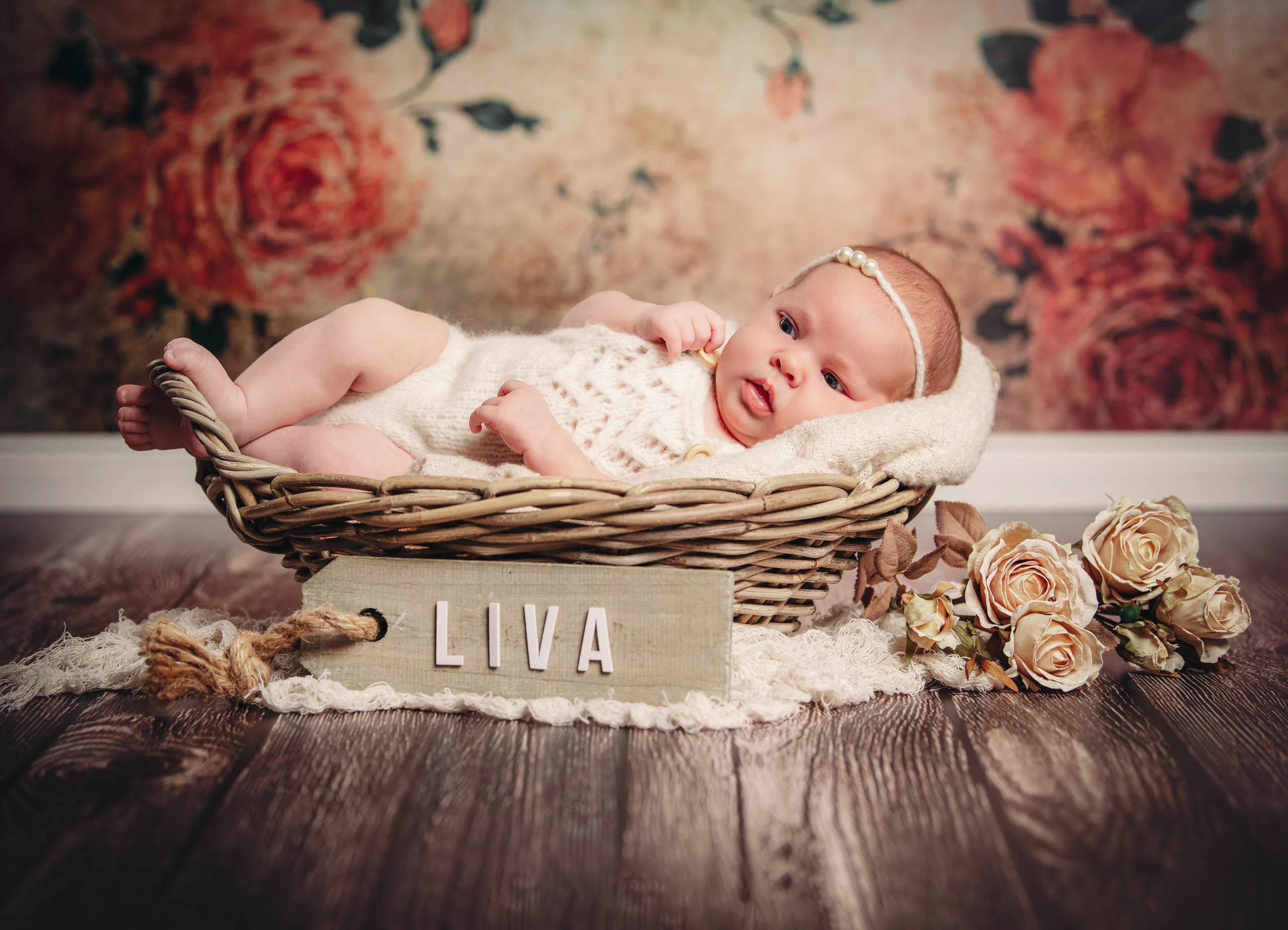 Babyfotos Neugeborene Fotogalerie 115 | Peter Lauritis Photography Baby im Weidenkorb vor Rosentapete, davor ein Namensschild
