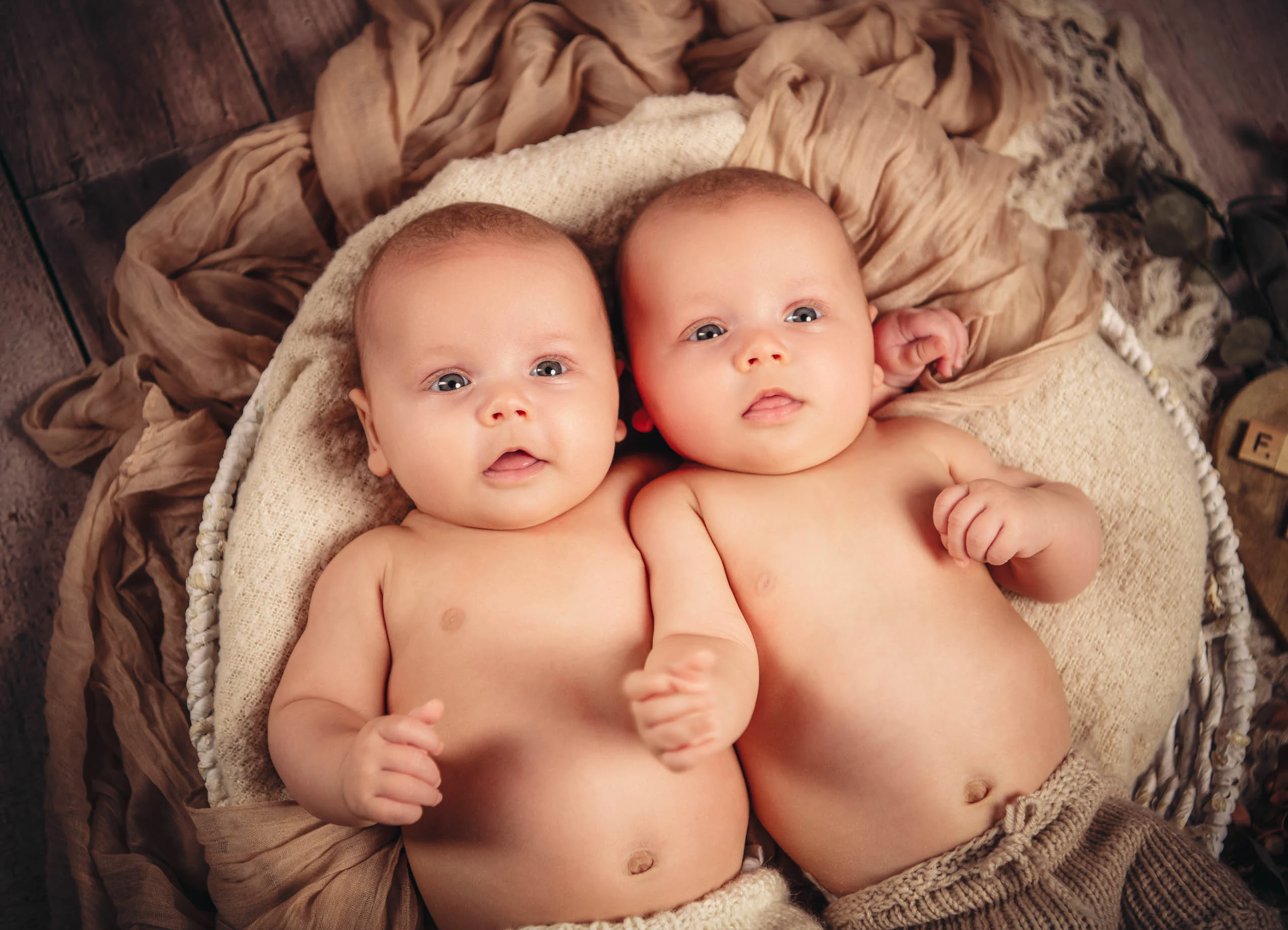 Babyfotos Neugeborene Fotogalerie 117 | Peter Lauritis Photography Zwei Babys liegen nebeneinander auf einer Decke und schauen in die Kamera