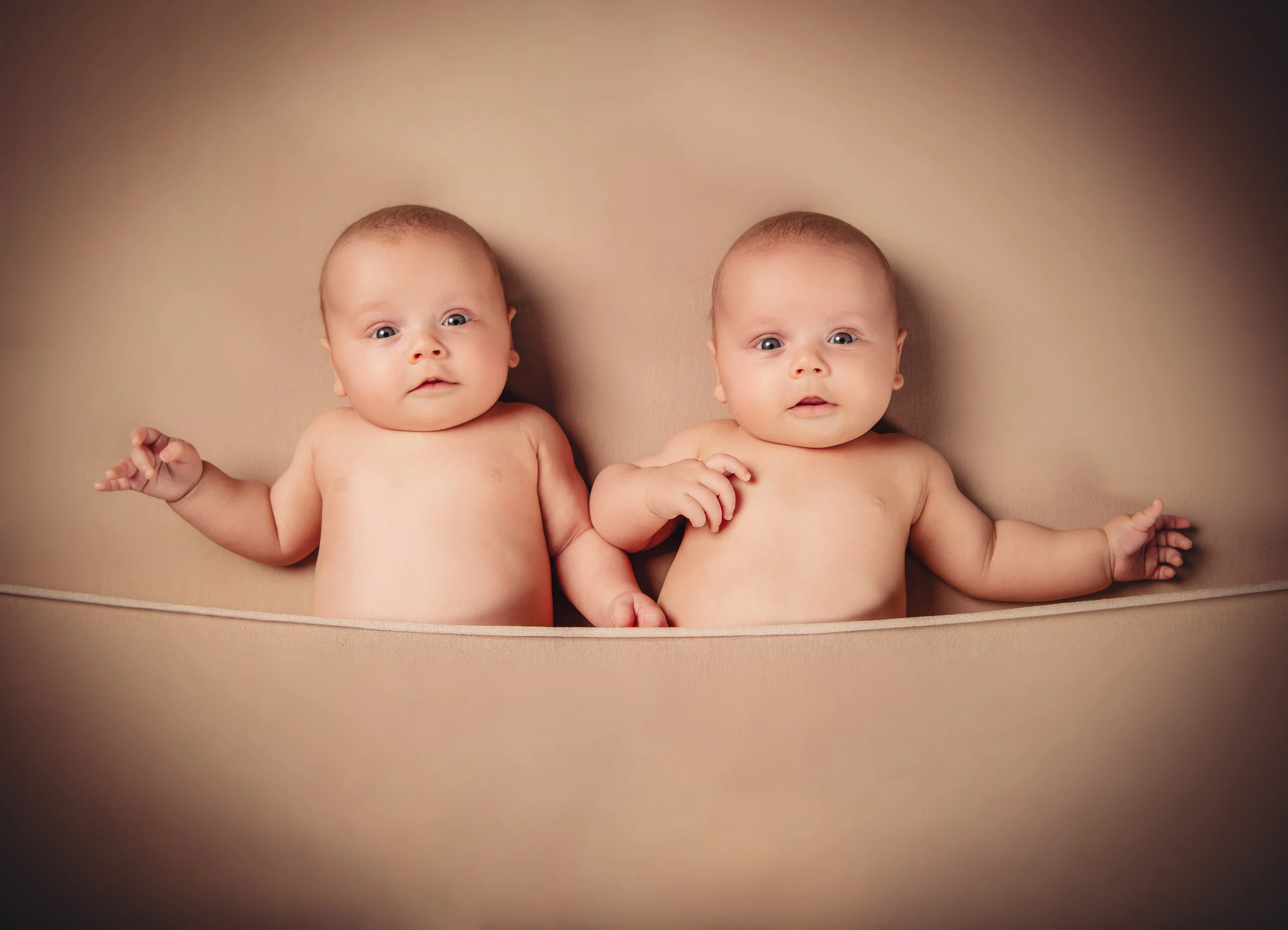 Babyfotos Neugeborene Fotogalerie 118 | Peter Lauritis Photography Zwei Babys liegen bäuchlings nebeneinander auf beigem Stoff