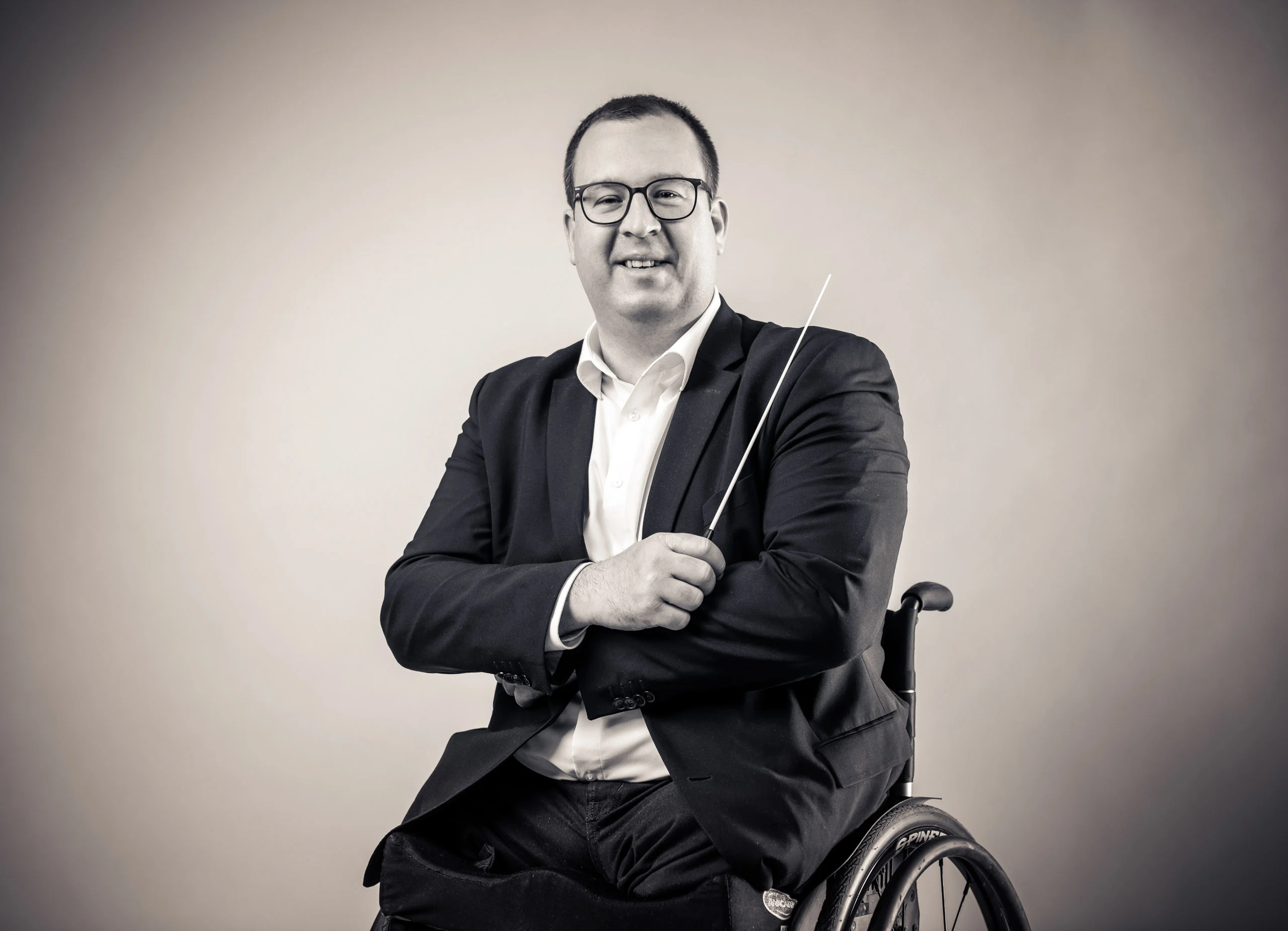 Business Portraits Fotogalerie 006 | Peter Lauritis Photography Mann im Rollstuhl mit Sakko hält lächelnd einen Taktstock