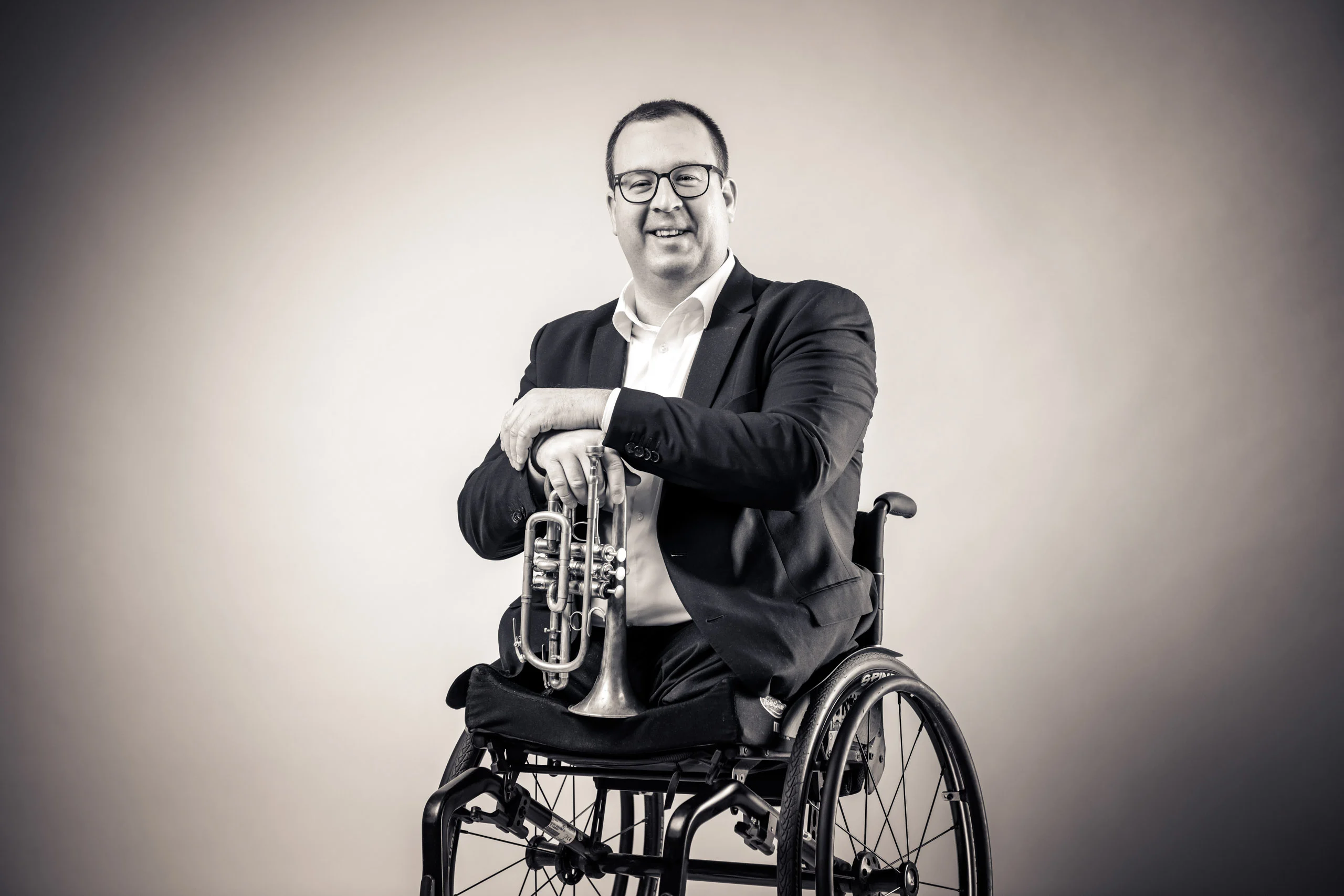 Business Portraits Fotogalerie 007 | Peter Lauritis Photography Mann im Rollstuhl mit Sakko hält ein Blechblasinstrument